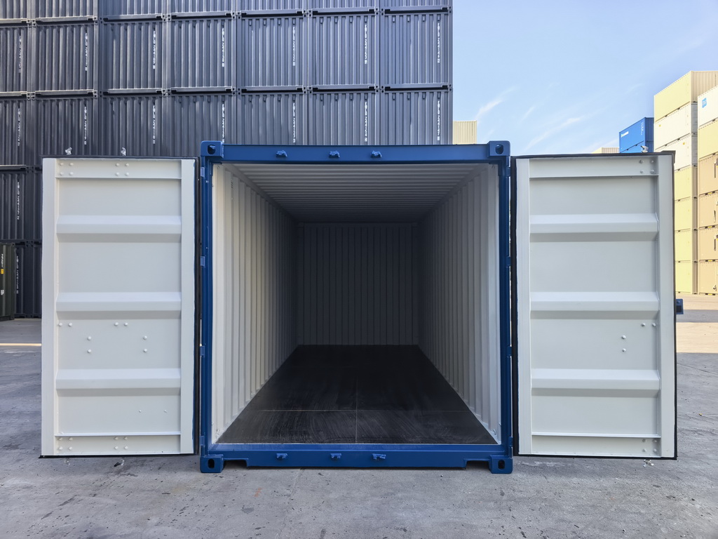 Open shipping container with sliding doors, showing empty interior, outdoors with buildings in background.