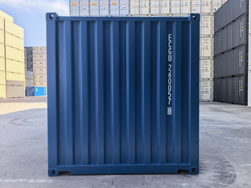 Blue shipping container with vertical ridges, identification code on right side, outdoors in a storage yard.