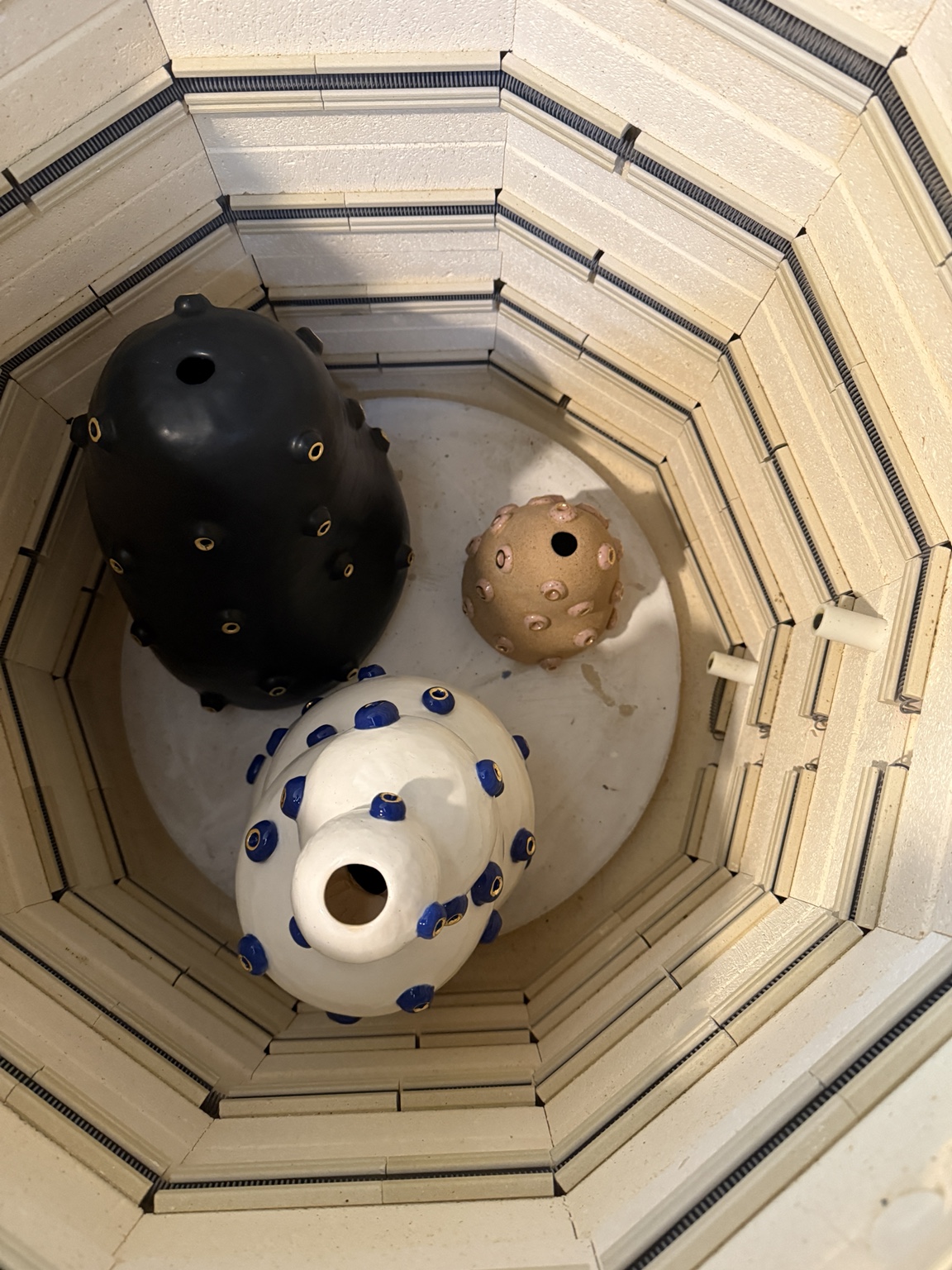 Three spherical objects with holes inside a layered, octagonal structure, viewed from above.