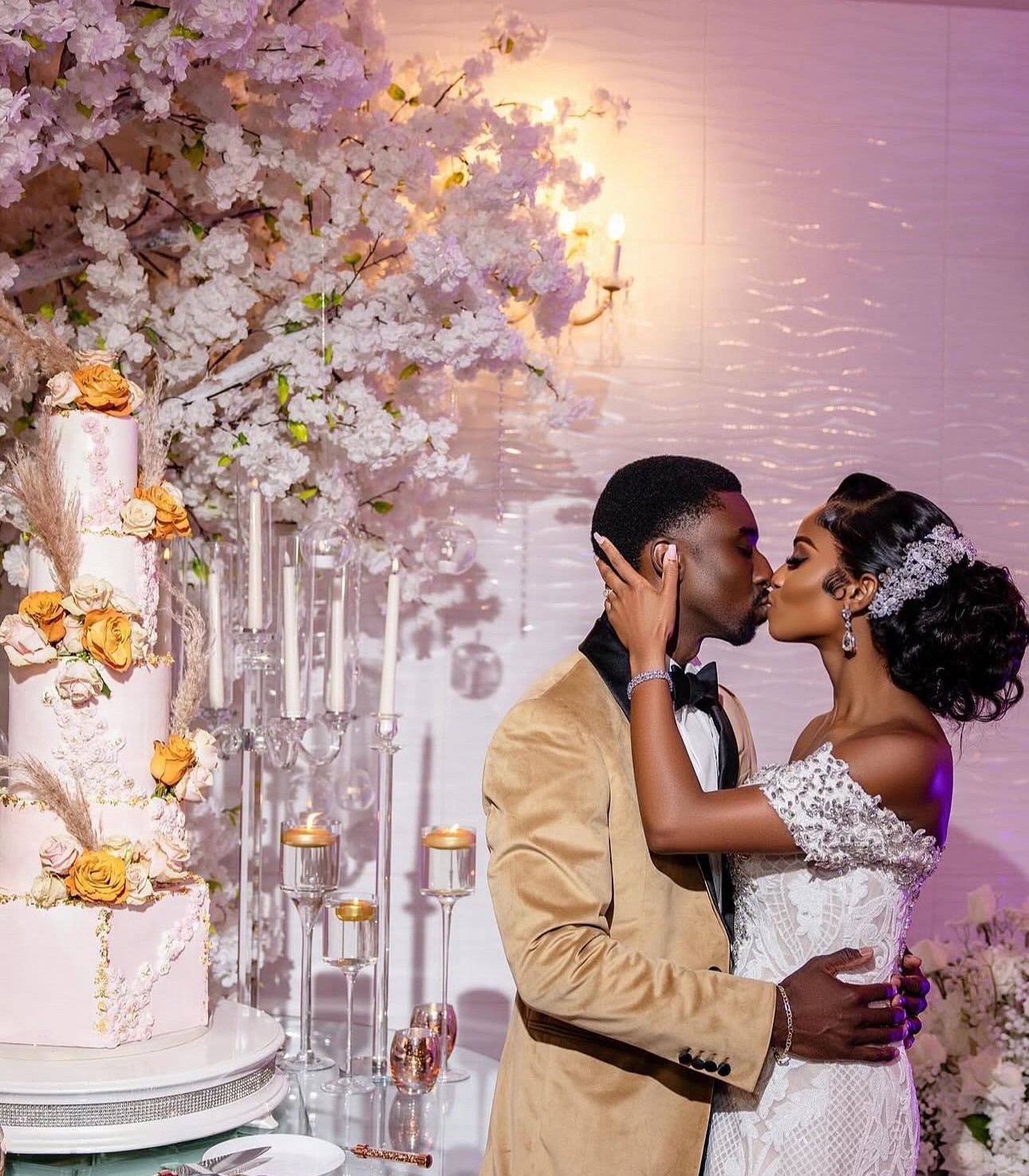 A couple in wedding attire face each other closely at a decorated wedding venue with flowers and candles.