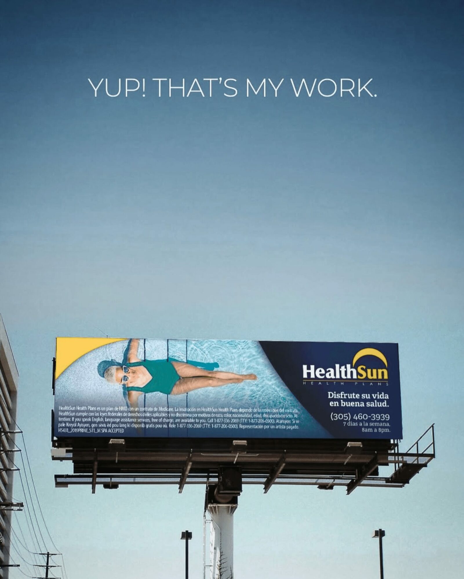 Billboard with a person lying on grass, blue sky background, and text 'YUP! THAT'S MY WORK.' at the top.