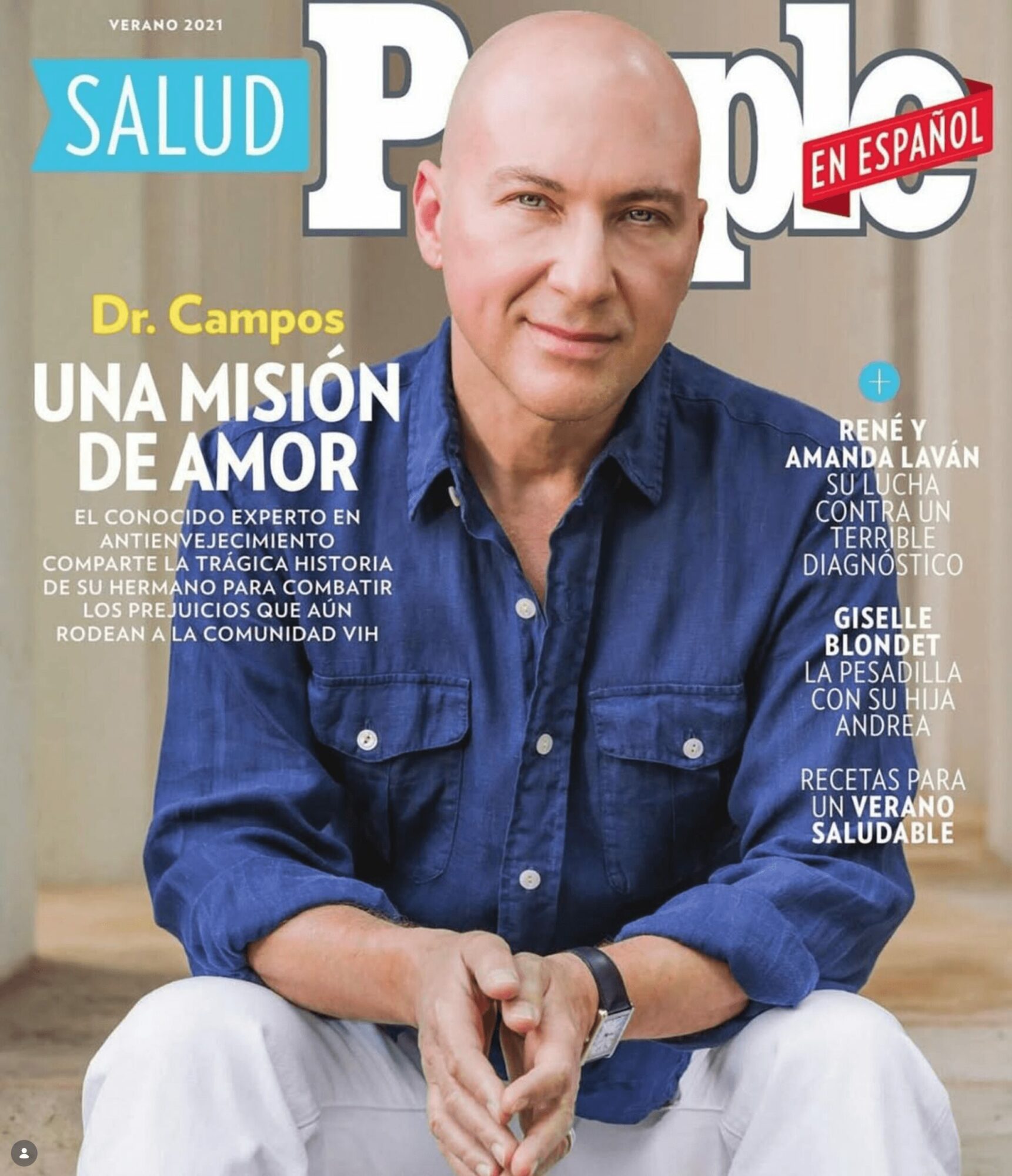 Man with a bald head wearing a blue shirt, sitting with hands clasped, smiling at the camera, magazine cover background.