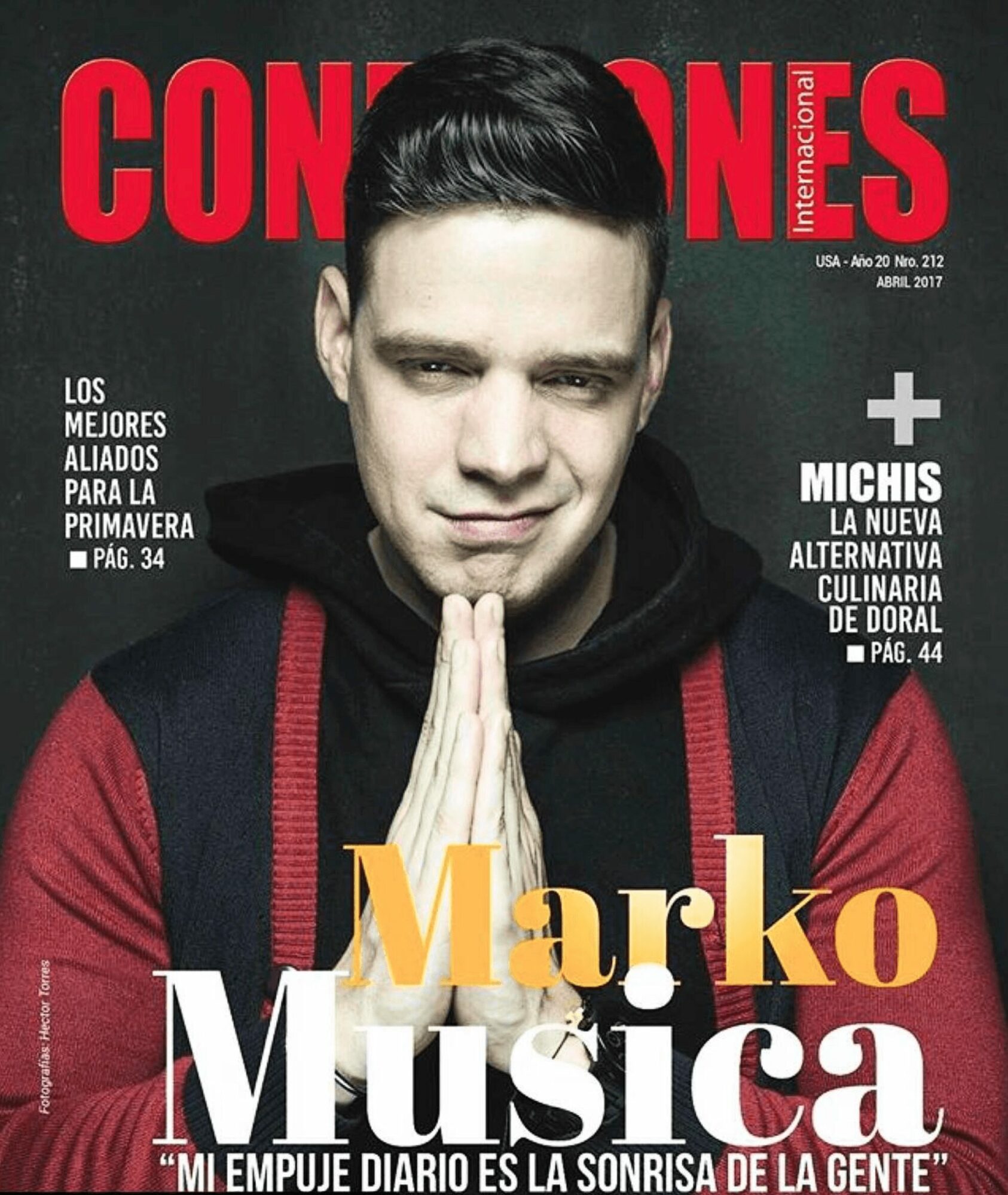 Man with dark hair in a hoodie, hands together, smiling slightly, magazine cover background with red and black text.