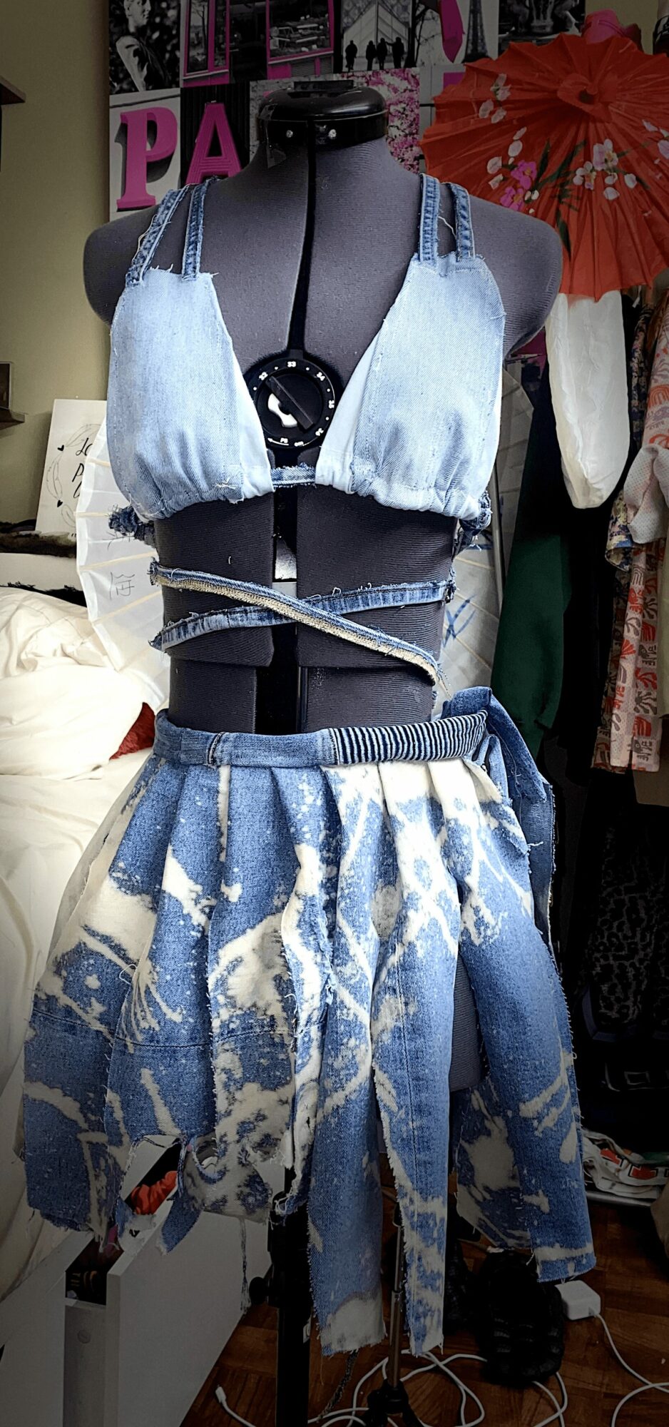 Clothing display with denim top, skirt, and accessories in a store setting.
