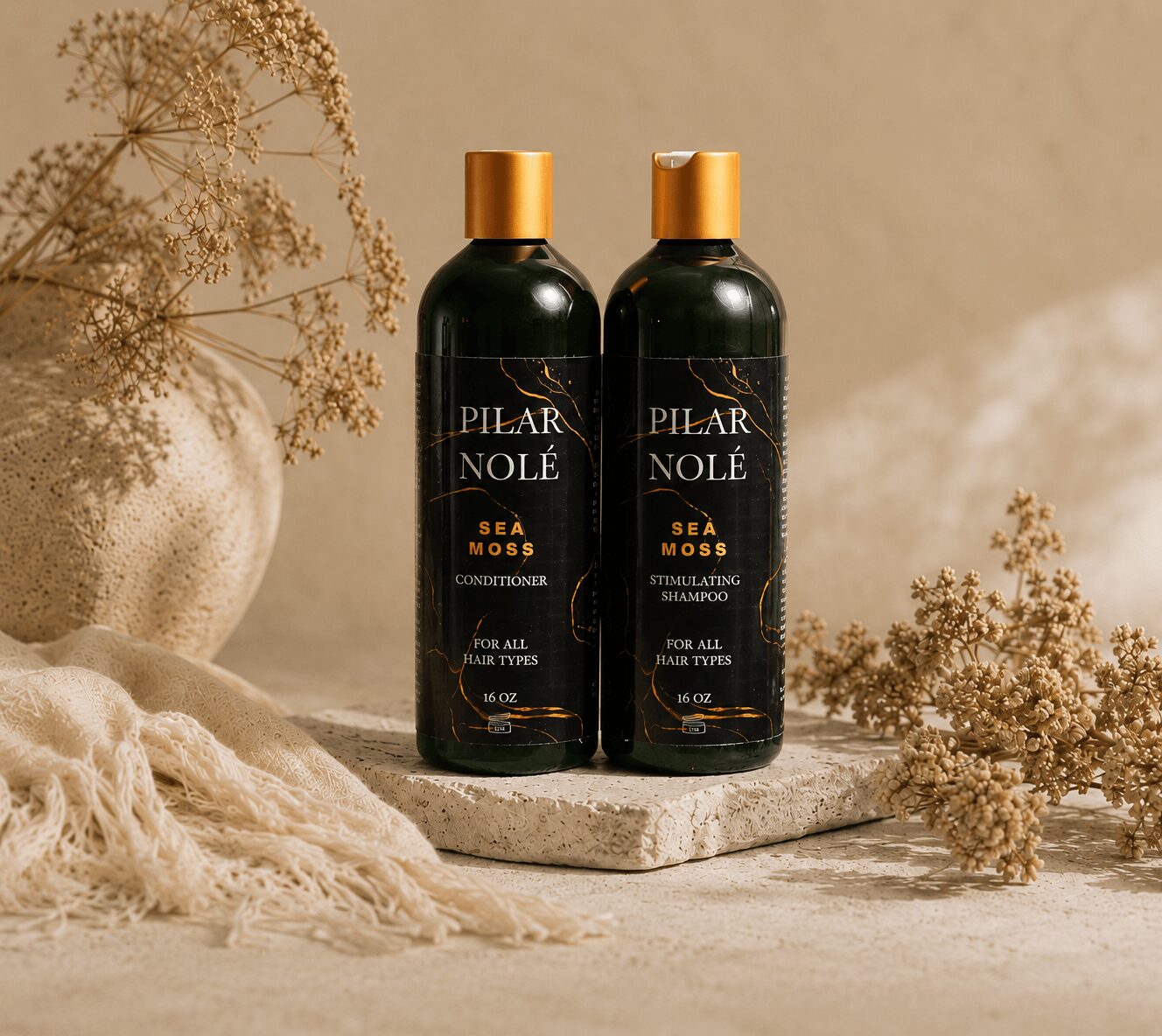 Two bottles of Pilar Nolé Sea Moss shampoo on a stone surface with dried flowers and a vase in the background.
