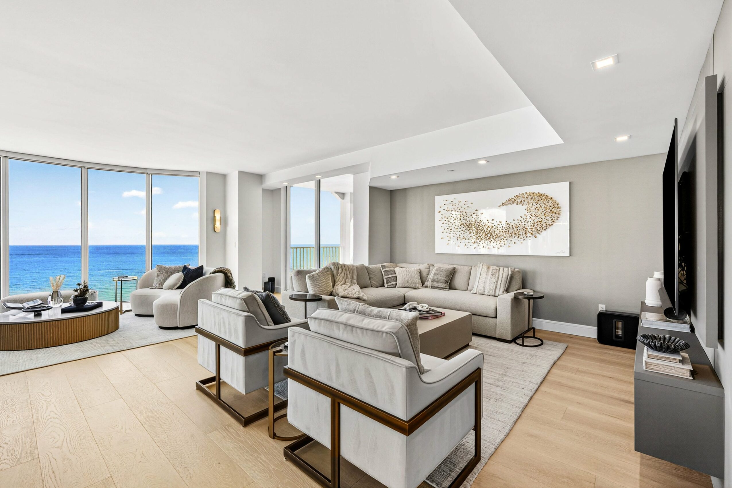Spacious living room with large windows overlooking the ocean, modern furniture, and a light-colored rug.