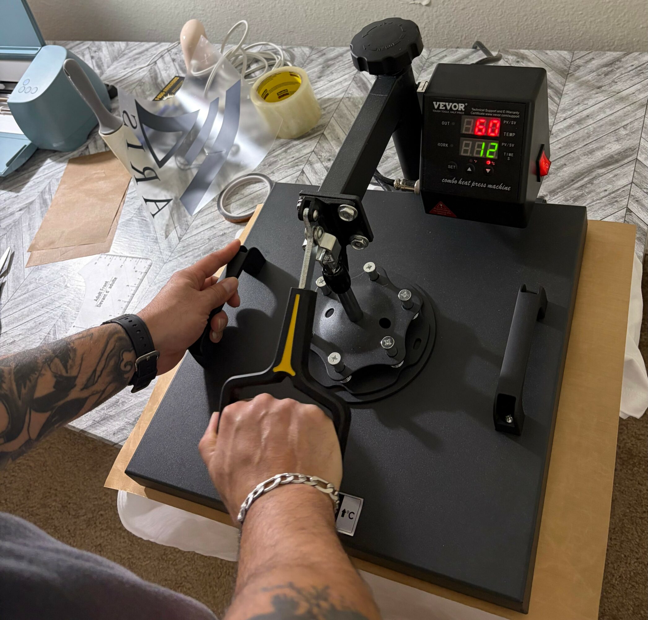 Person operating a robotic arm on a black base, with a control box displaying temperature and humidity, on a table.