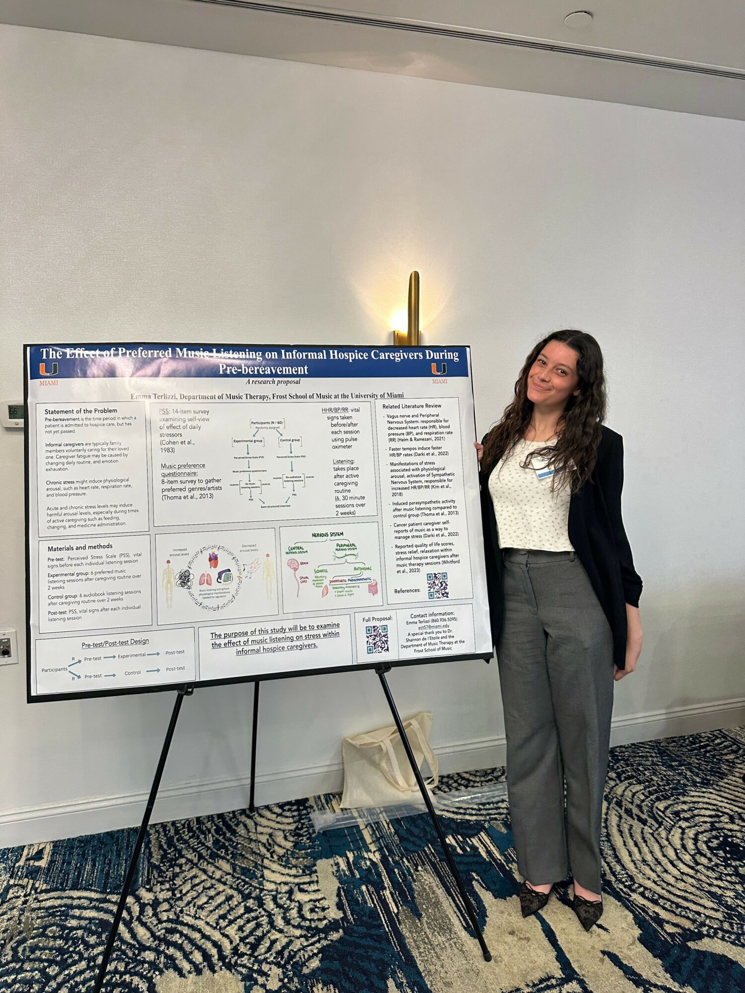 Woman standing next to a large scientific poster on a stand, in a room with patterned carpet.