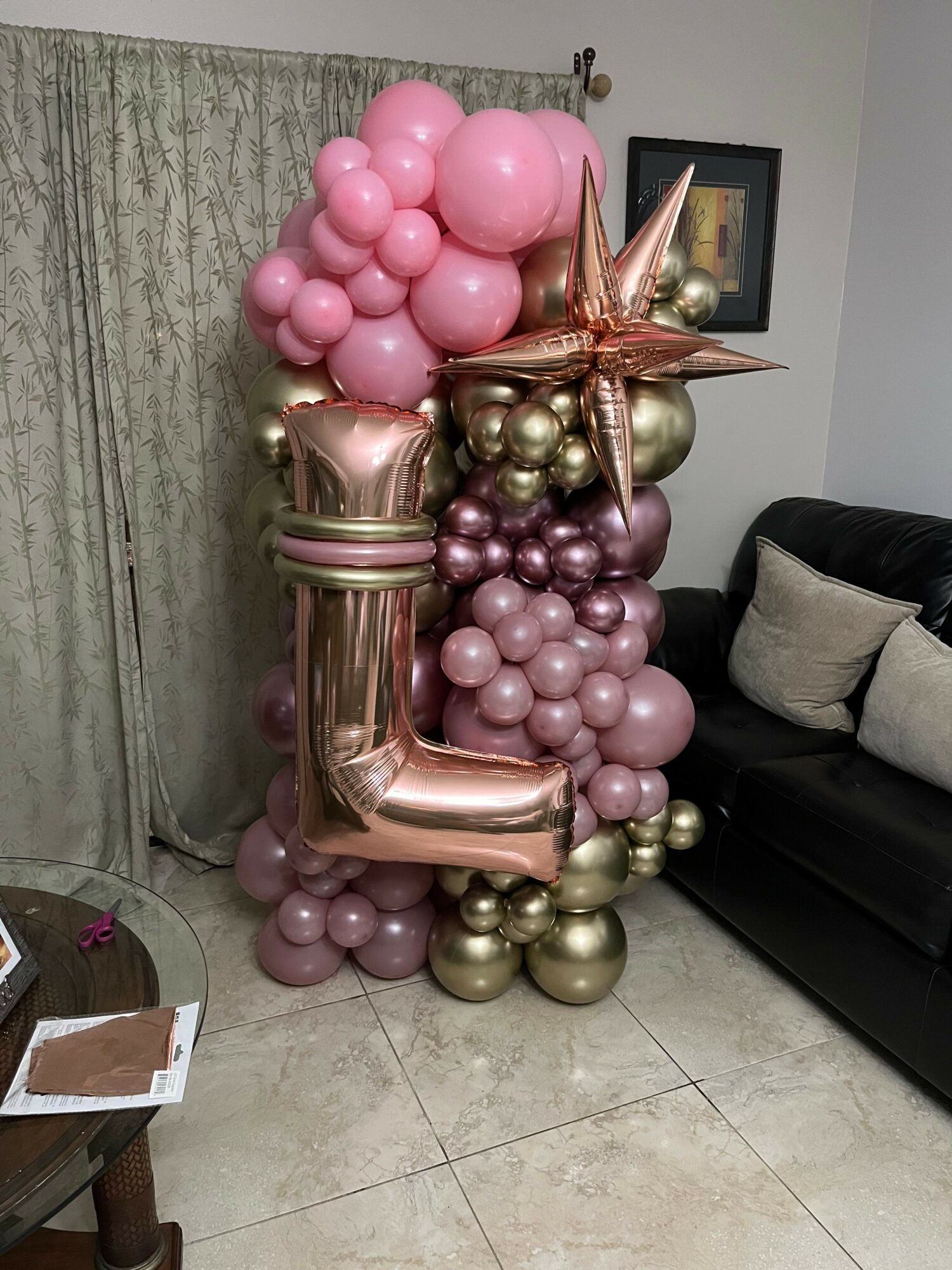 Balloon arrangement with pink, gold, and rose gold balloons, including star and number-shaped balloons, on a tiled floor.