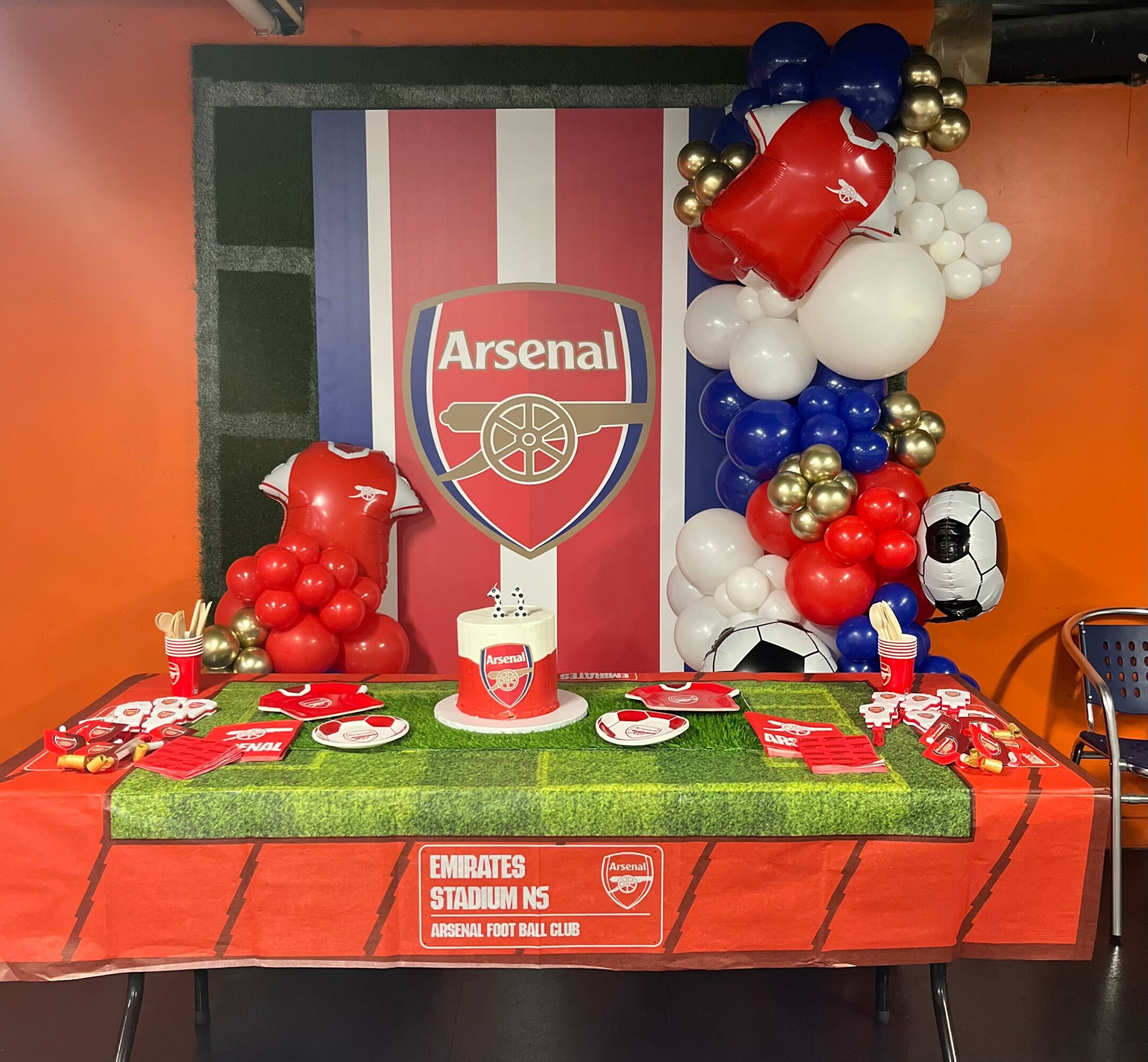 Football-themed party setup with balloons, Arsenal logo, and a table with football decorations.