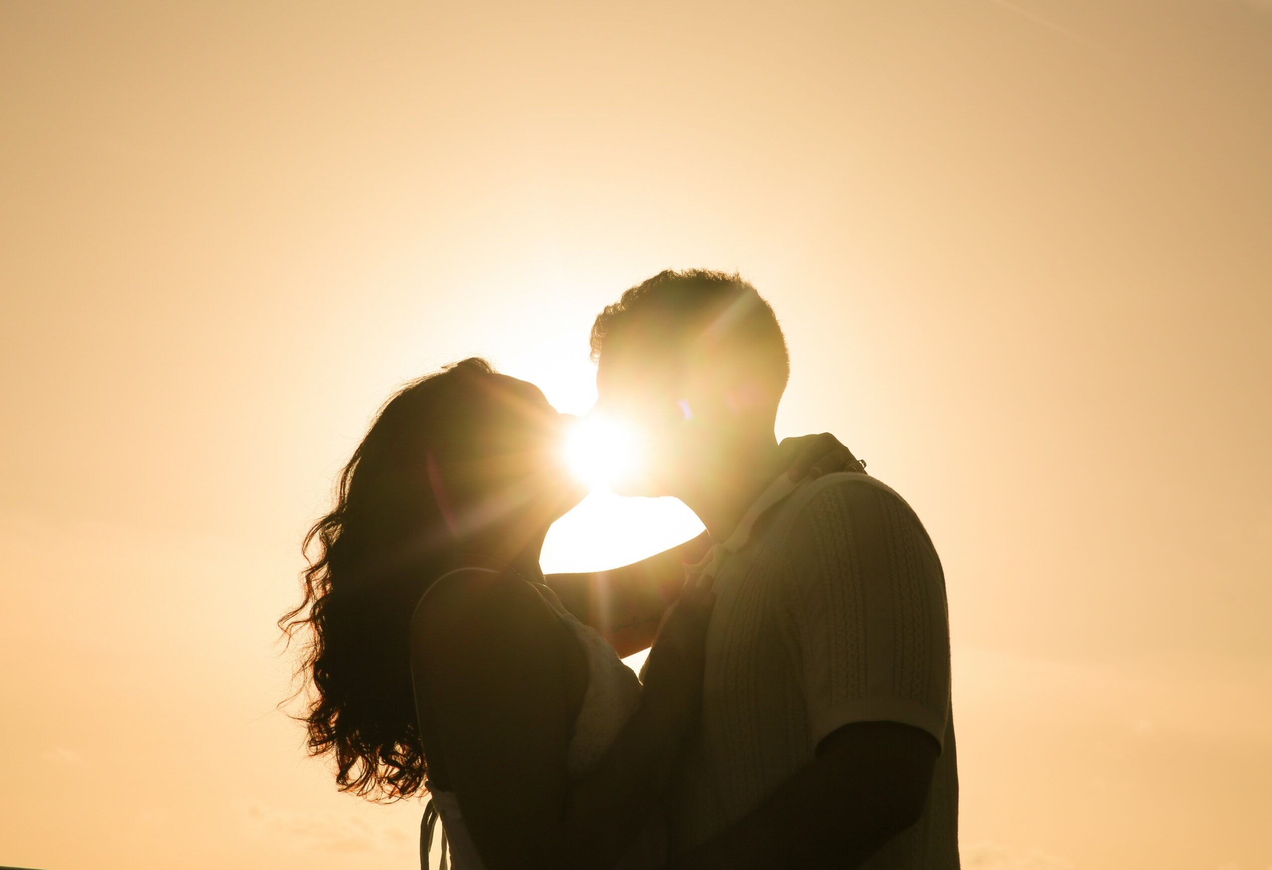 Two people face each other with the sun behind them, creating a bright glow around their heads.