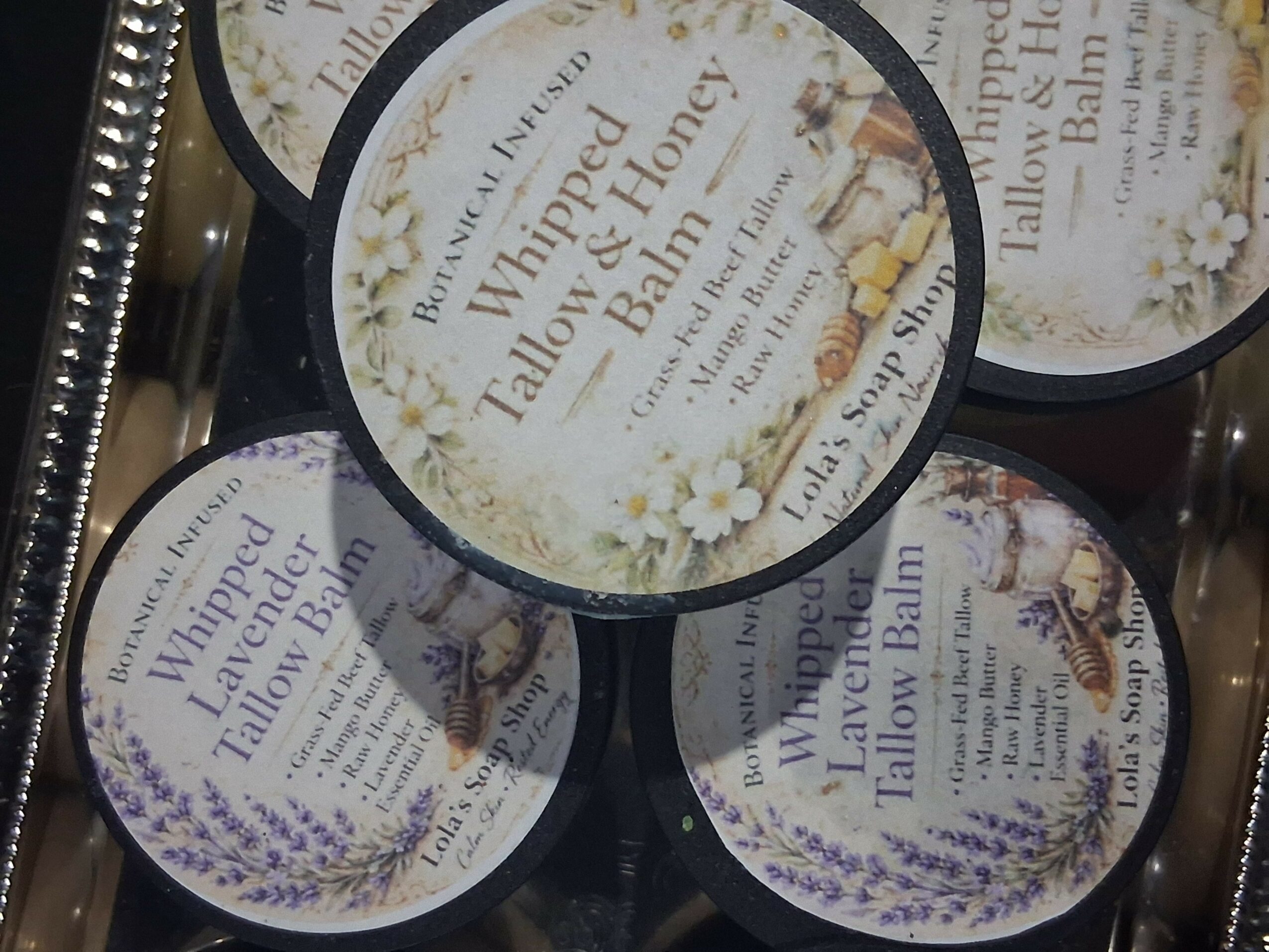 Four containers of Wampu Tallow Balm with floral labels, stacked together.