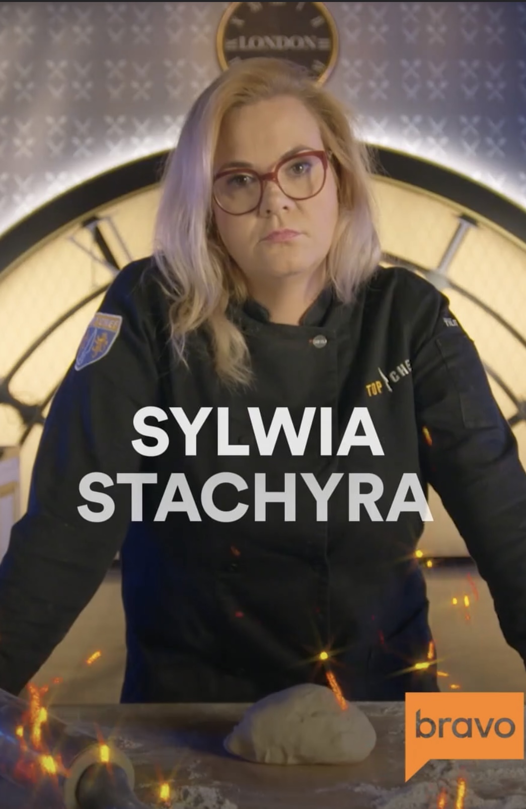 Woman with glasses and blonde hair in police uniform standing in front of a clock, with text 'SYLWIA STACHYRA'.