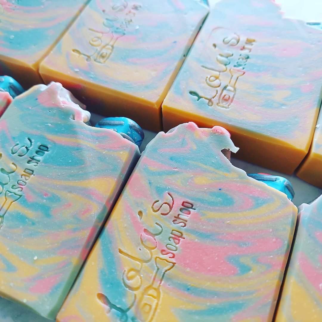 Colorful soap bars with pastel swirls and embossed text, arranged in a pattern.
