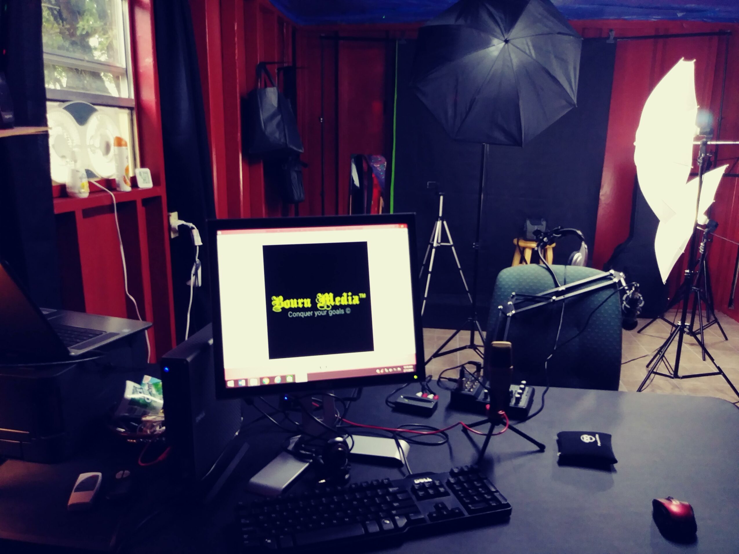 Photo of a photography or video studio with lighting equipment, a computer monitor, and a camera setup.