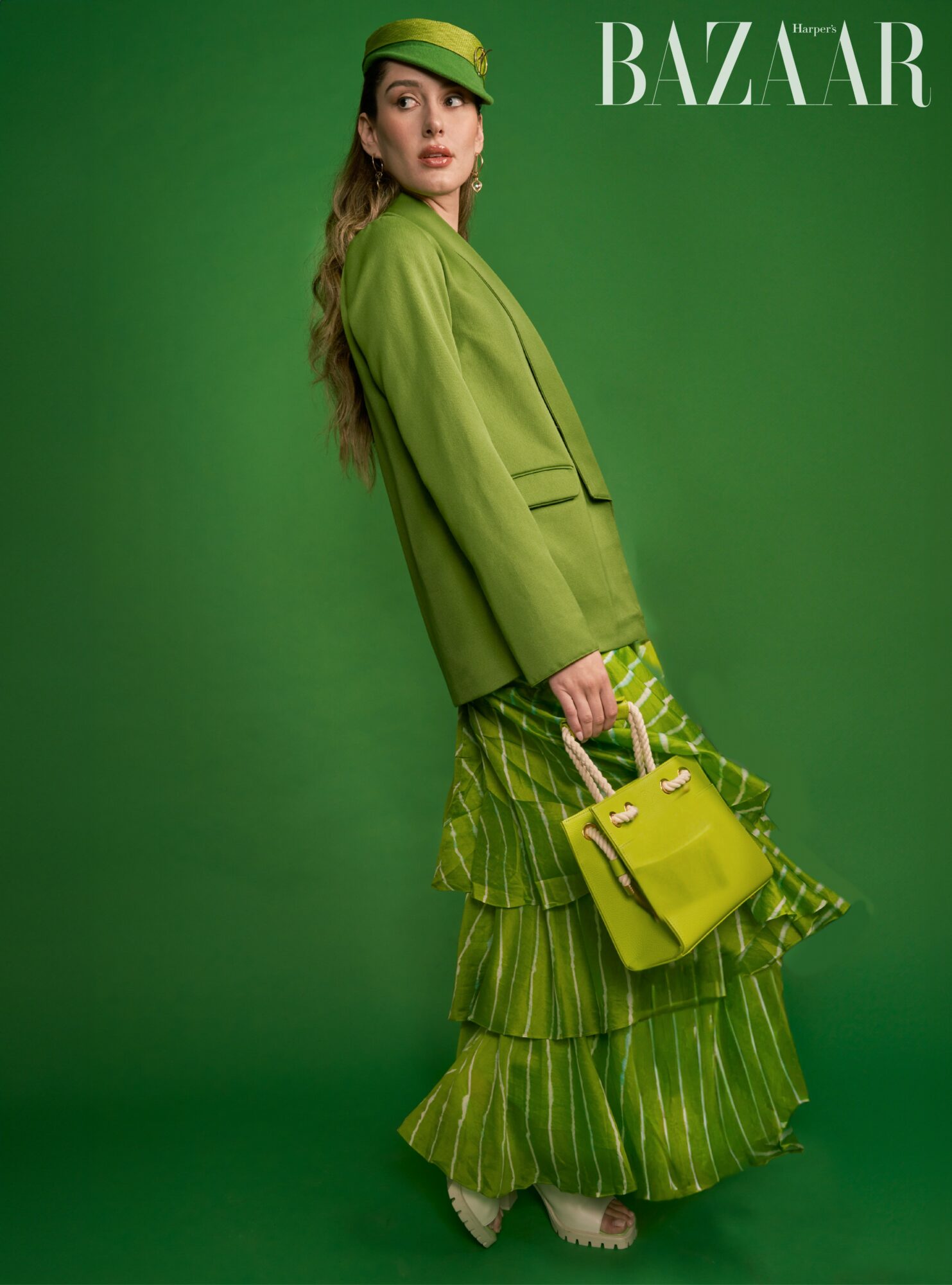 Woman in green outfit holding a yellow handbag against a green background, magazine logo in top right corner.