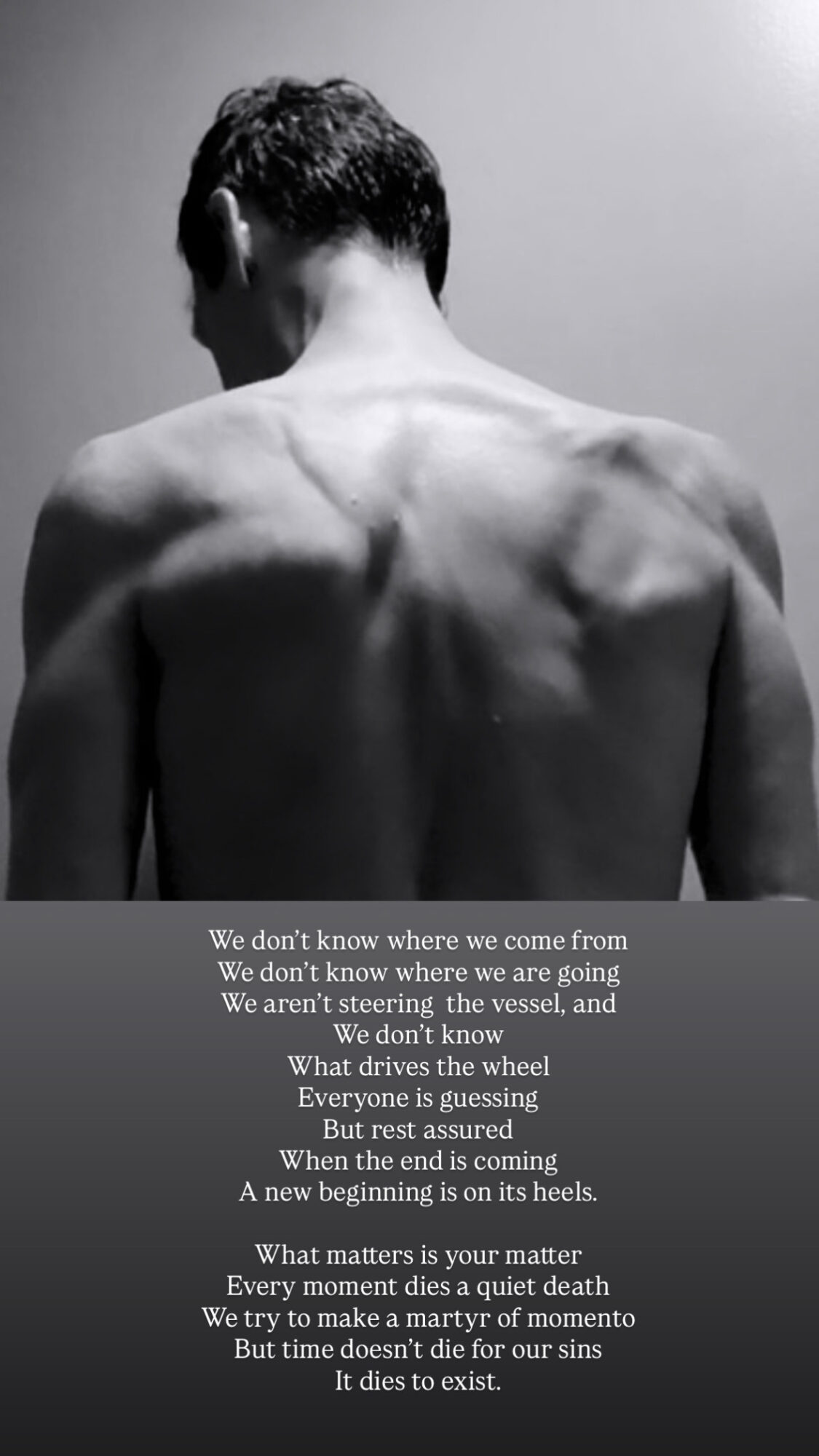 Back view of a shirtless person with visible shoulder and back muscles, facing a plain wall.