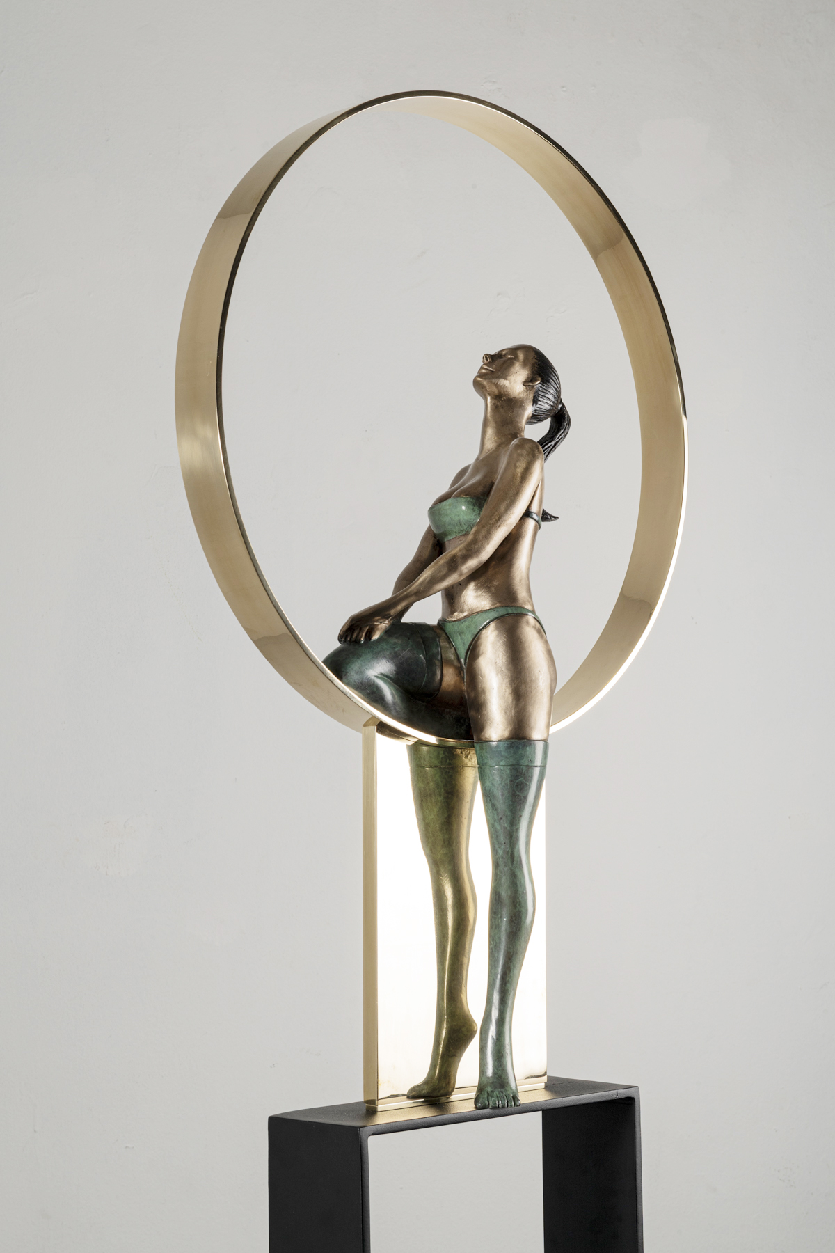 Sculpture of a woman with a mirror frame, standing on a black base, with metallic finish and green accents.