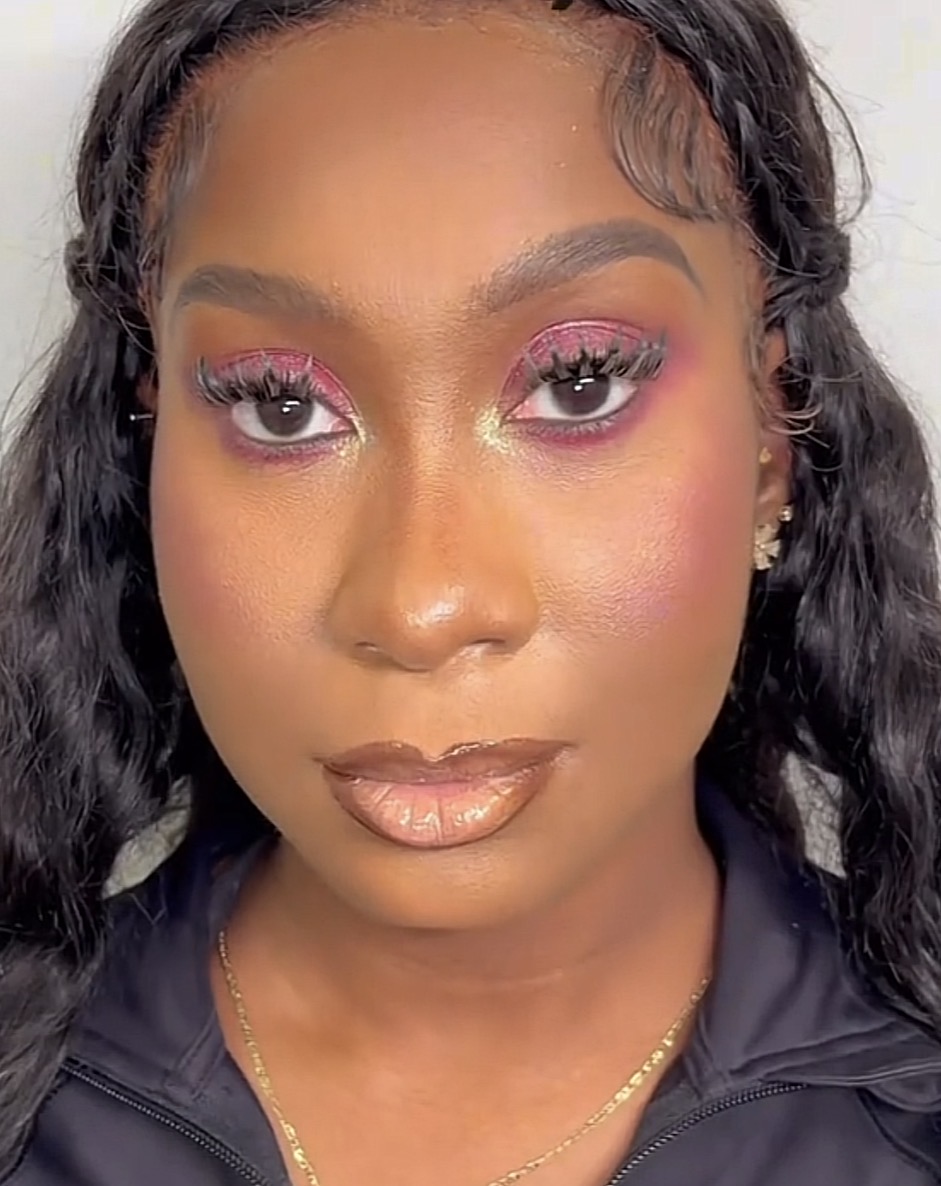 Close-up of a woman with makeup, curly hair, and earrings, looking directly at the camera.