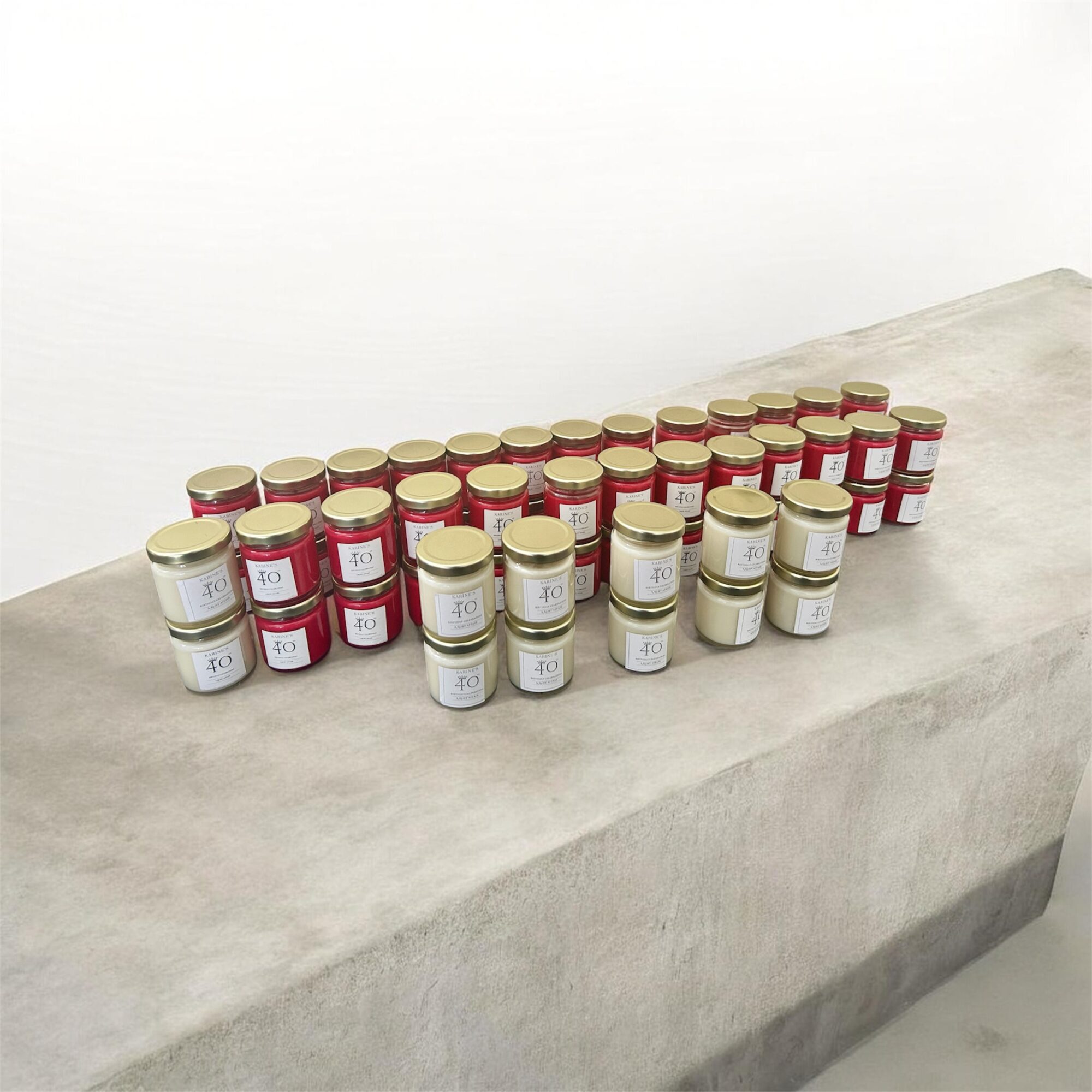 Multiple small jars with red and white labels arranged on a concrete surface, against a plain white background.