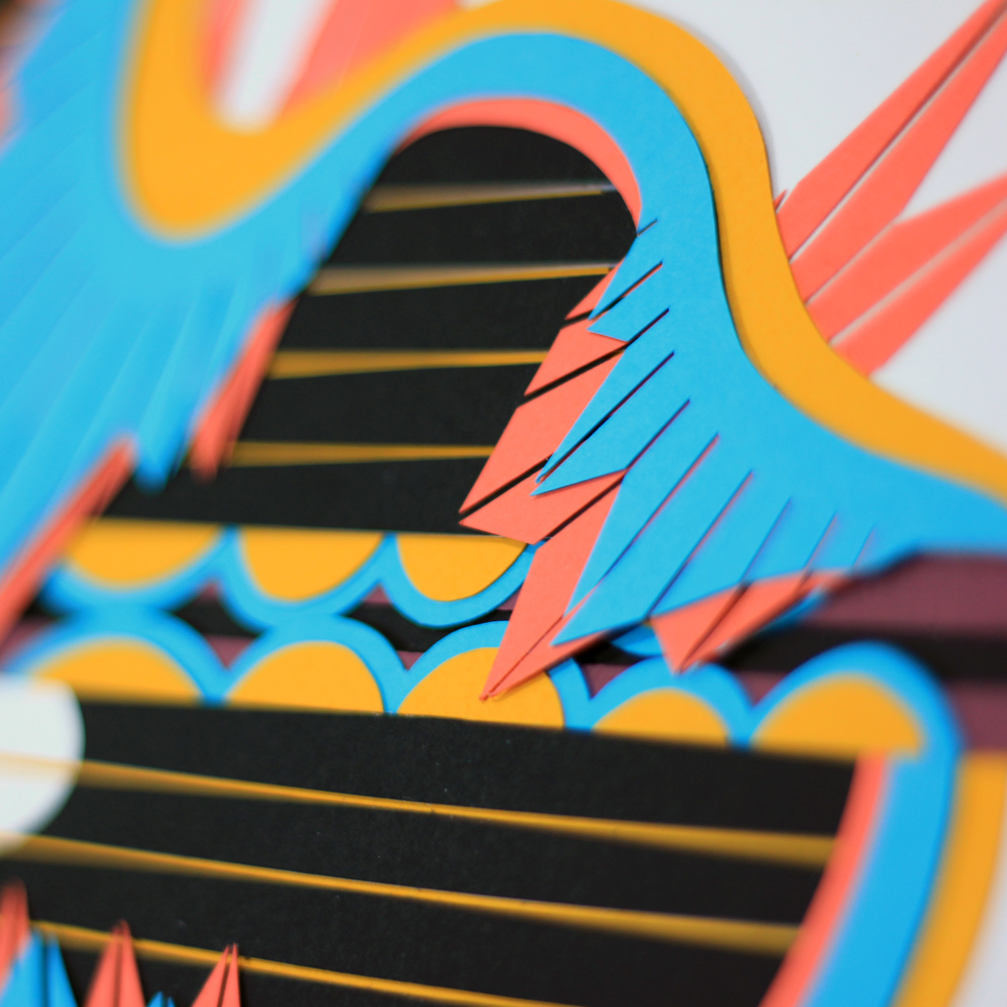 Close-up of colorful layered paper or cardboard artwork with abstract shapes and patterns.