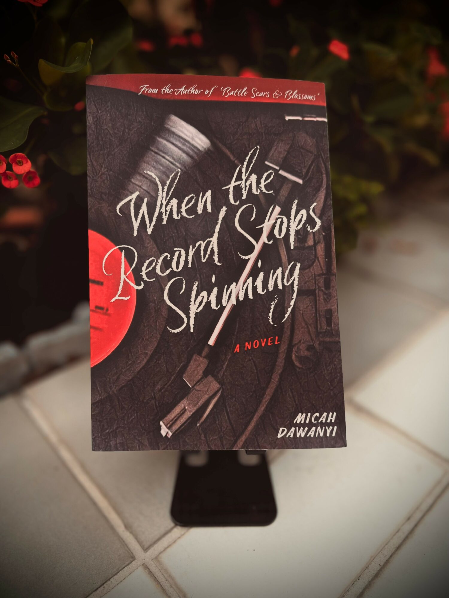Book cover titled 'When the Record Stops Spinning' by Micah Dawany, with a black and white record player image and red accents.