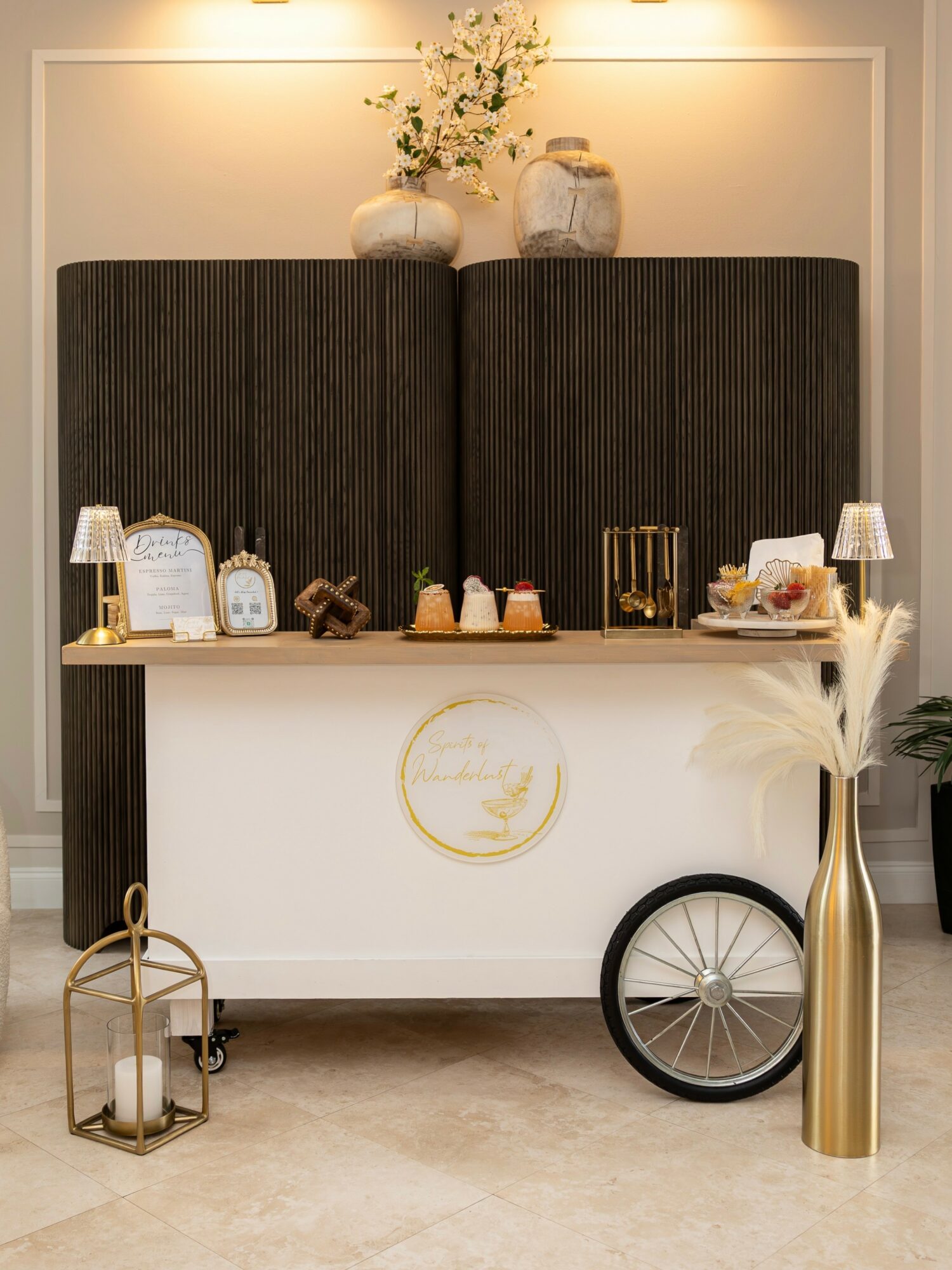 Decorative cart with flowers, candles, and ornaments, against a dark backdrop with warm lighting, in a neutral-toned room.