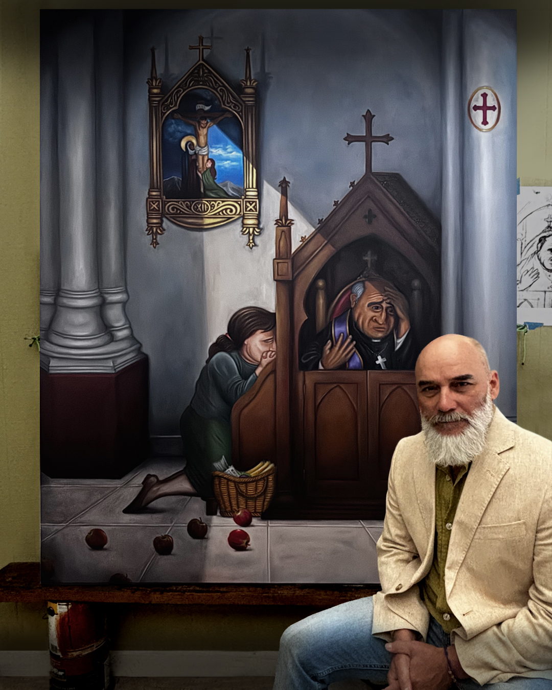A man with a white beard and beige jacket sits in front of a religious mural inside a church, with a cross and religious figures.