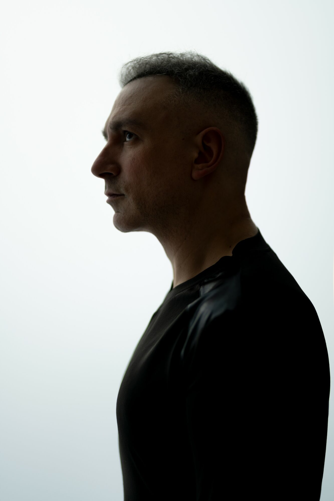 Profile of a man with short hair, facing left, against a light background.