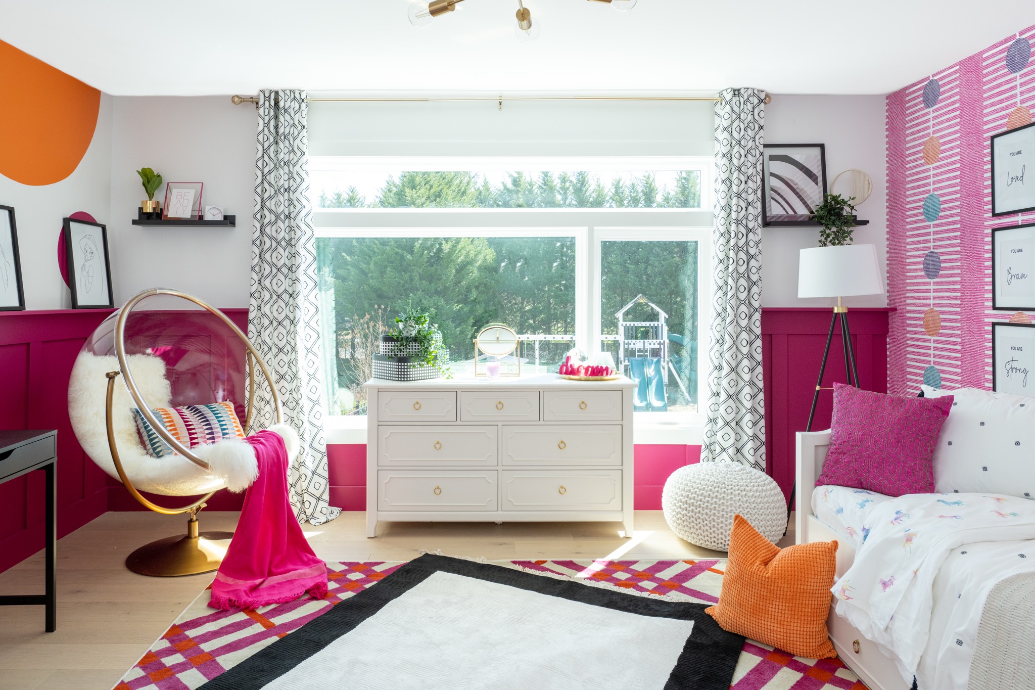 Bright bedroom with large window, white dresser, bed with pillows, pink and purple walls, and a hanging chair.