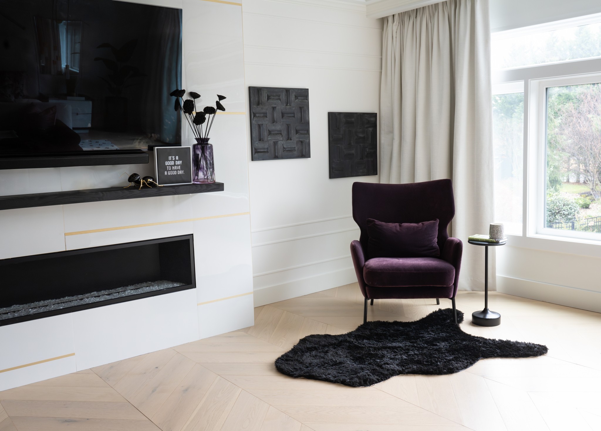 Living room with a purple armchair, black rug, window with curtains, and wall-mounted TV.