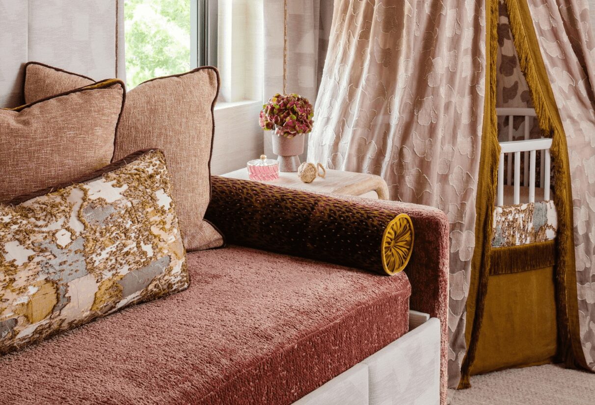 Close-up of a sofa with cushions, a side table with a flower vase, and curtains in a cozy room.