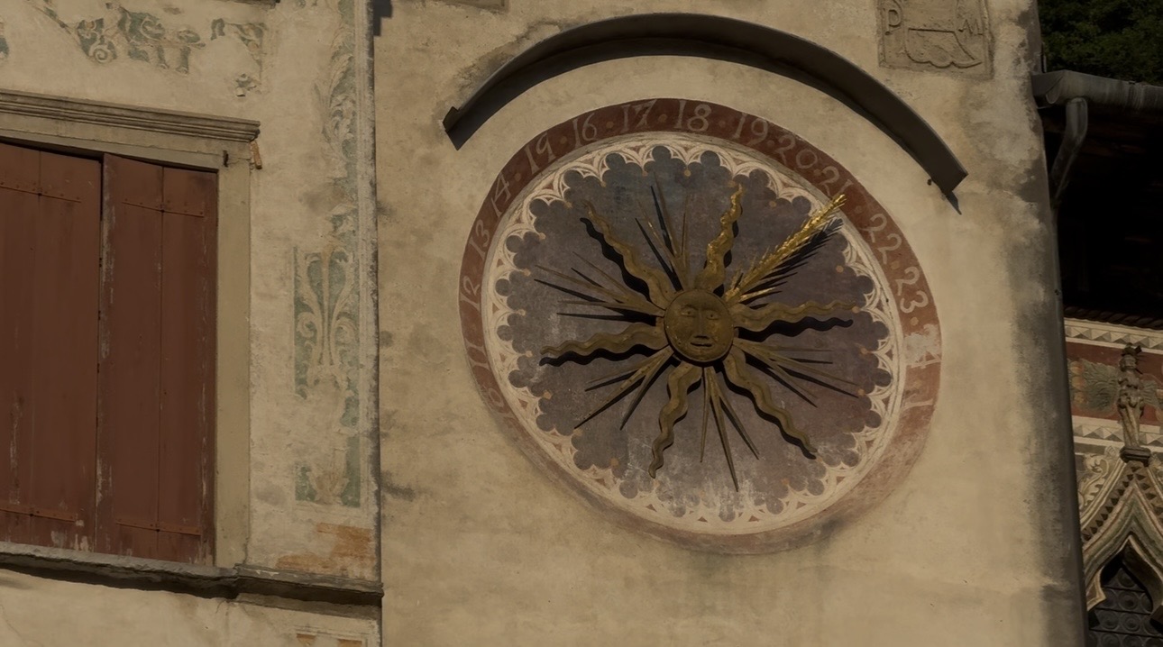 Clock with sun and moon symbols, showing time, on a building wall.