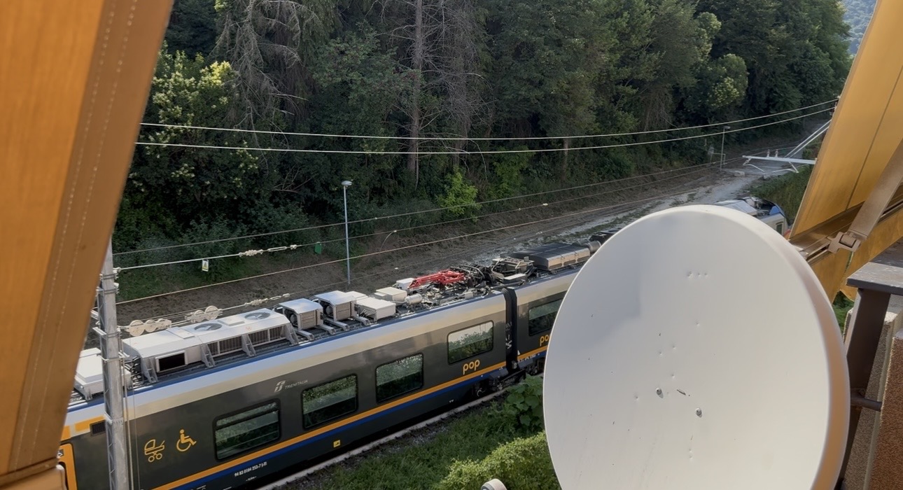 View from a high vantage point showing a train on tracks with trees in the background.