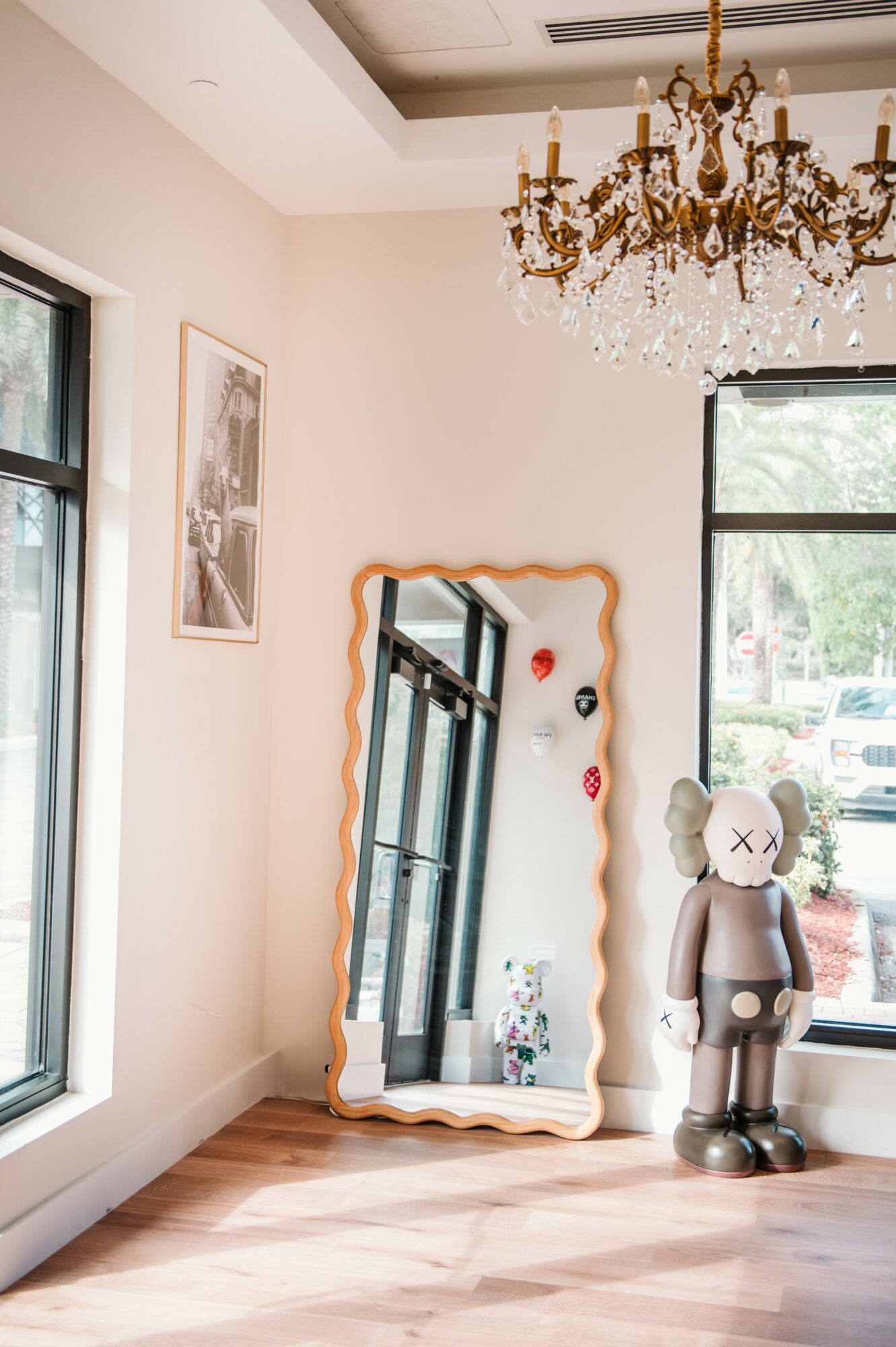 Interior corner with a large mirror, a balloon sculpture, and a chandelier hanging from the ceiling.