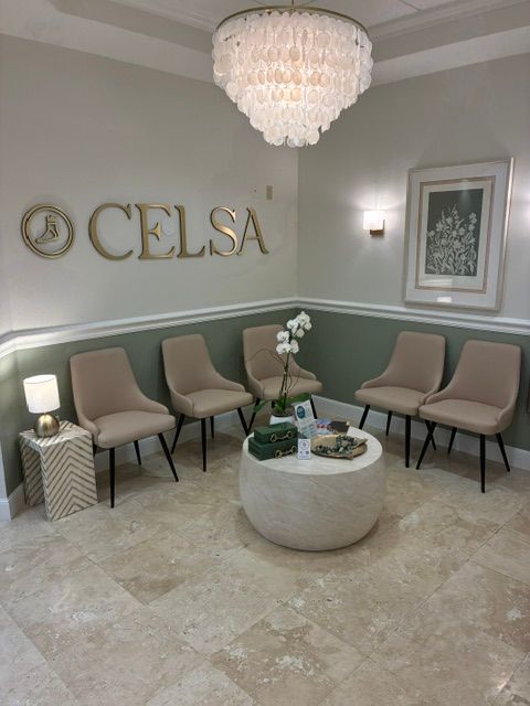 Waiting area with four beige chairs, a round table, and a decorative lamp, with