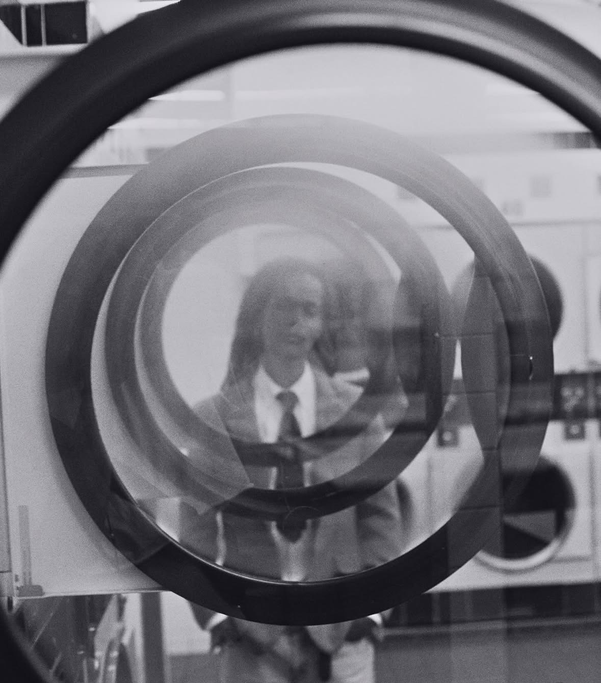 Reflection of a woman in a circular mirror, with a blurred background, black and white image.