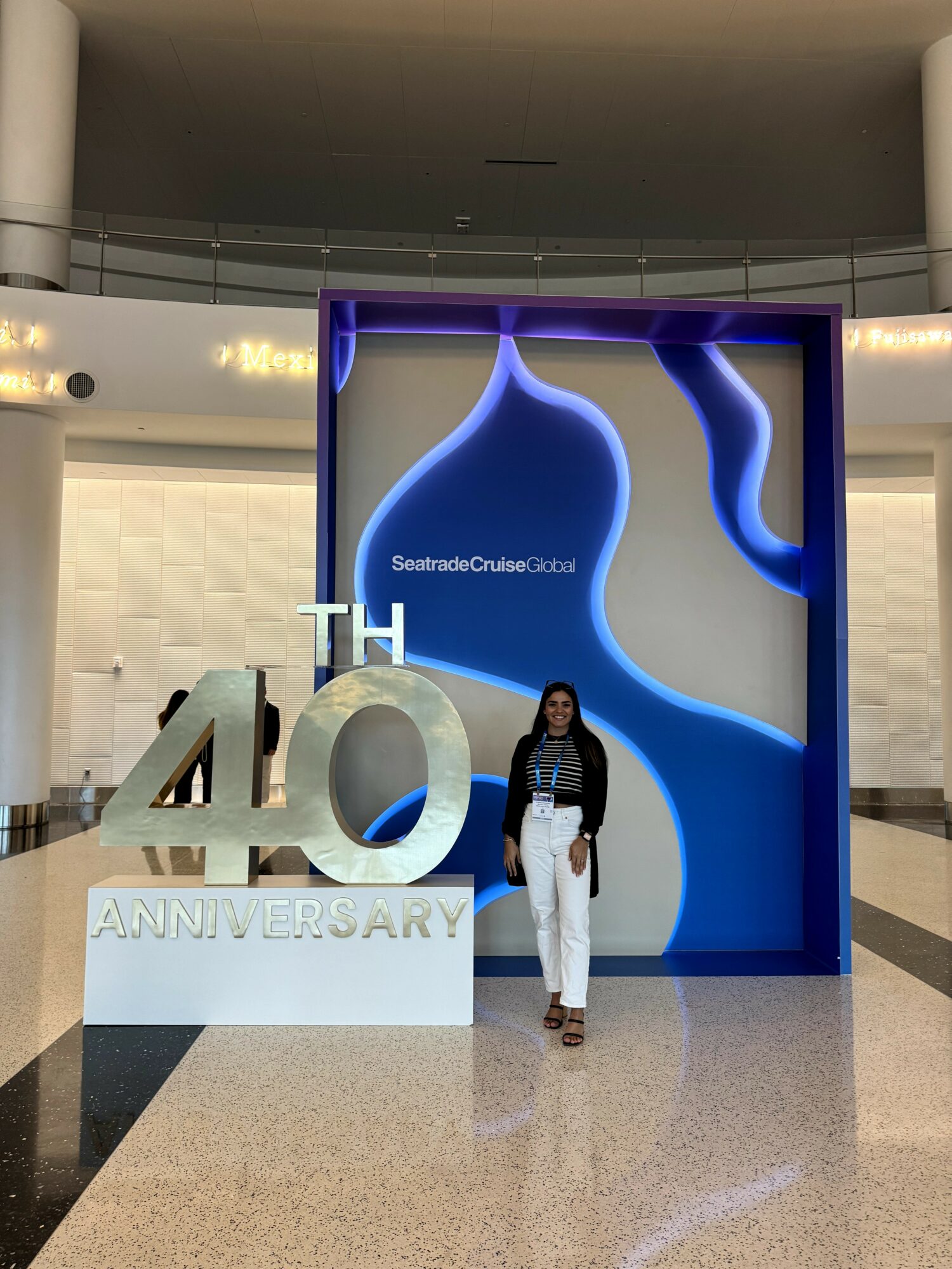 Person standing in front of a large 40th anniversary display with blue abstract shapes and text.