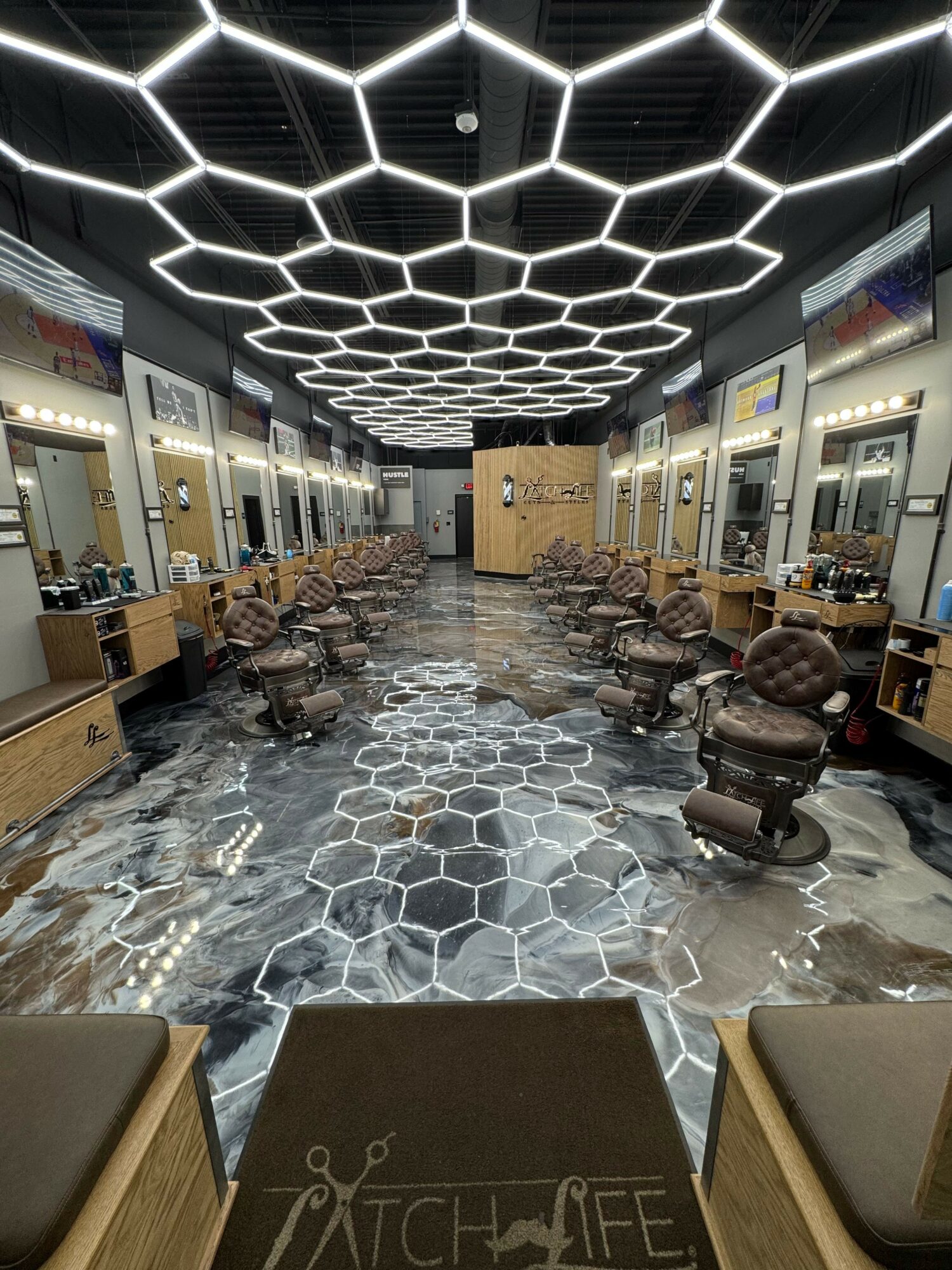Indoor space with hexagonal light pattern on ceiling, chairs, tables, and a patterned floor, possibly a lounge or waiting area.