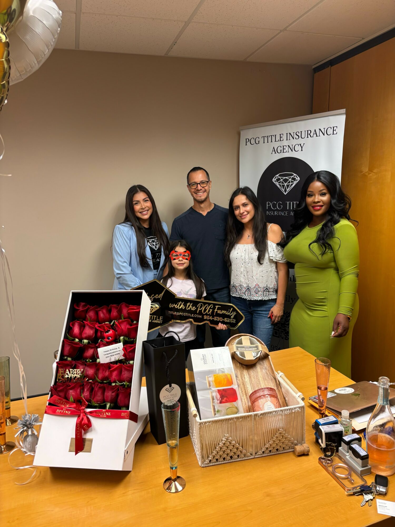 Four people stand behind a table with gift boxes and promotional items, in front of a PUG Title Insurance Agency banner.