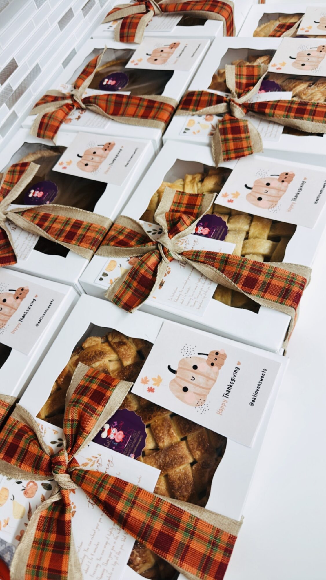 Multiple gift boxes wrapped with plaid ribbons and cards, arranged on a surface.