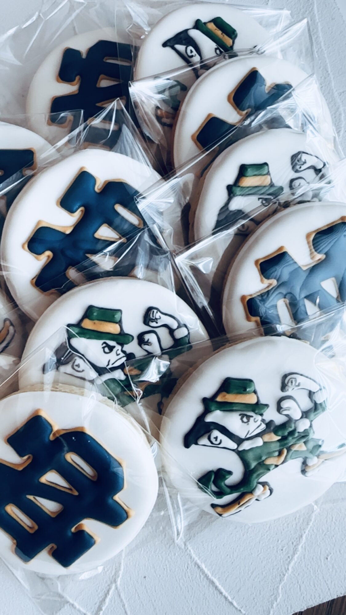 Cookies decorated with blue and gold symbols, wrapped in clear plastic, on a white surface.