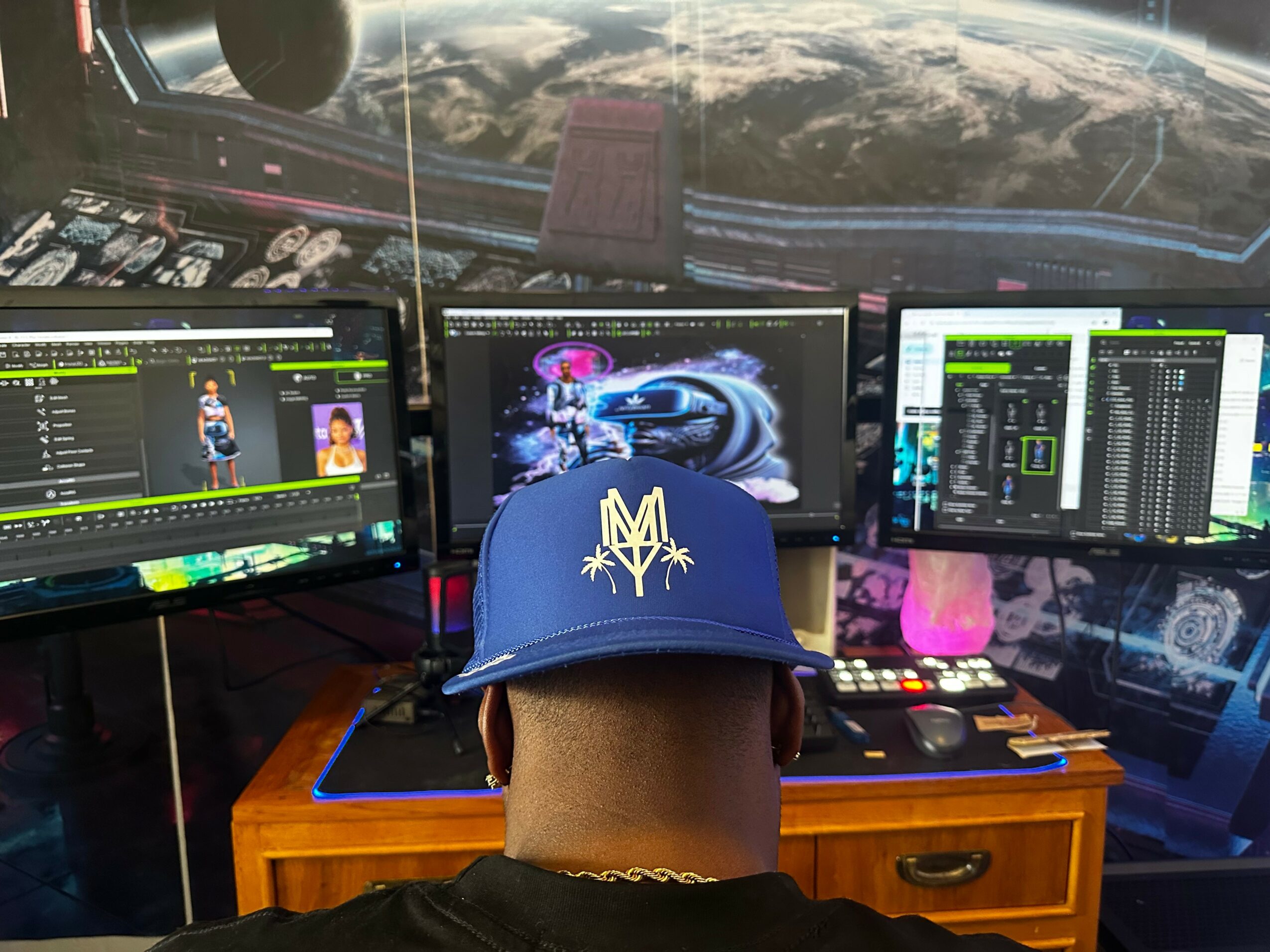 Person wearing a blue cap with a yellow emblem, working at a desk with three monitors displaying space-themed and data visuals, space station view outside.