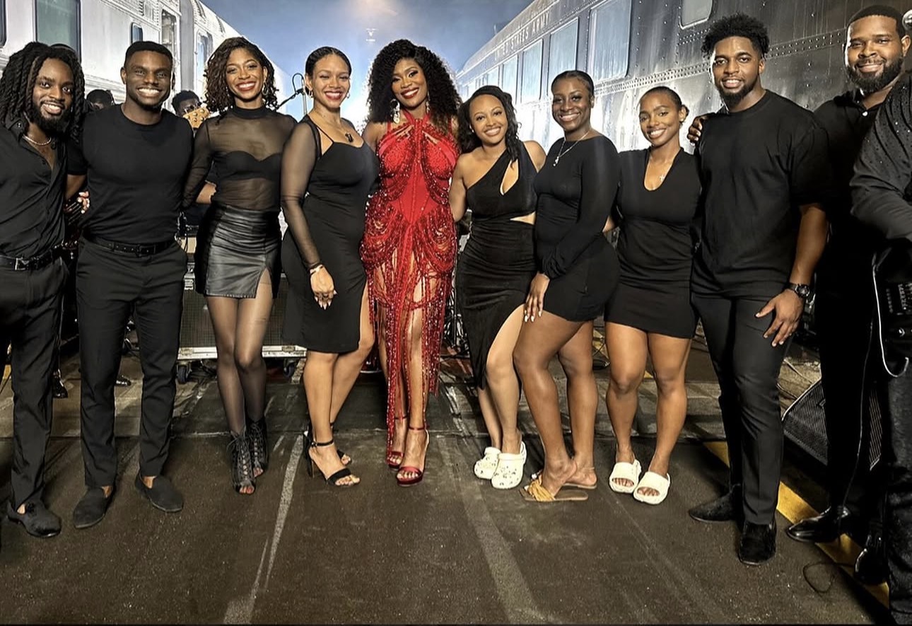 Group of ten people dressed in black and red, standing together indoors, smiling for the photo.