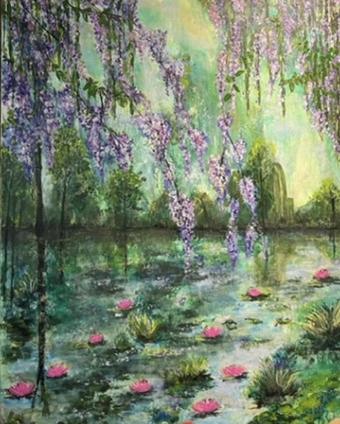 Water lilies floating on a pond with hanging purple flowers and green trees in the background.