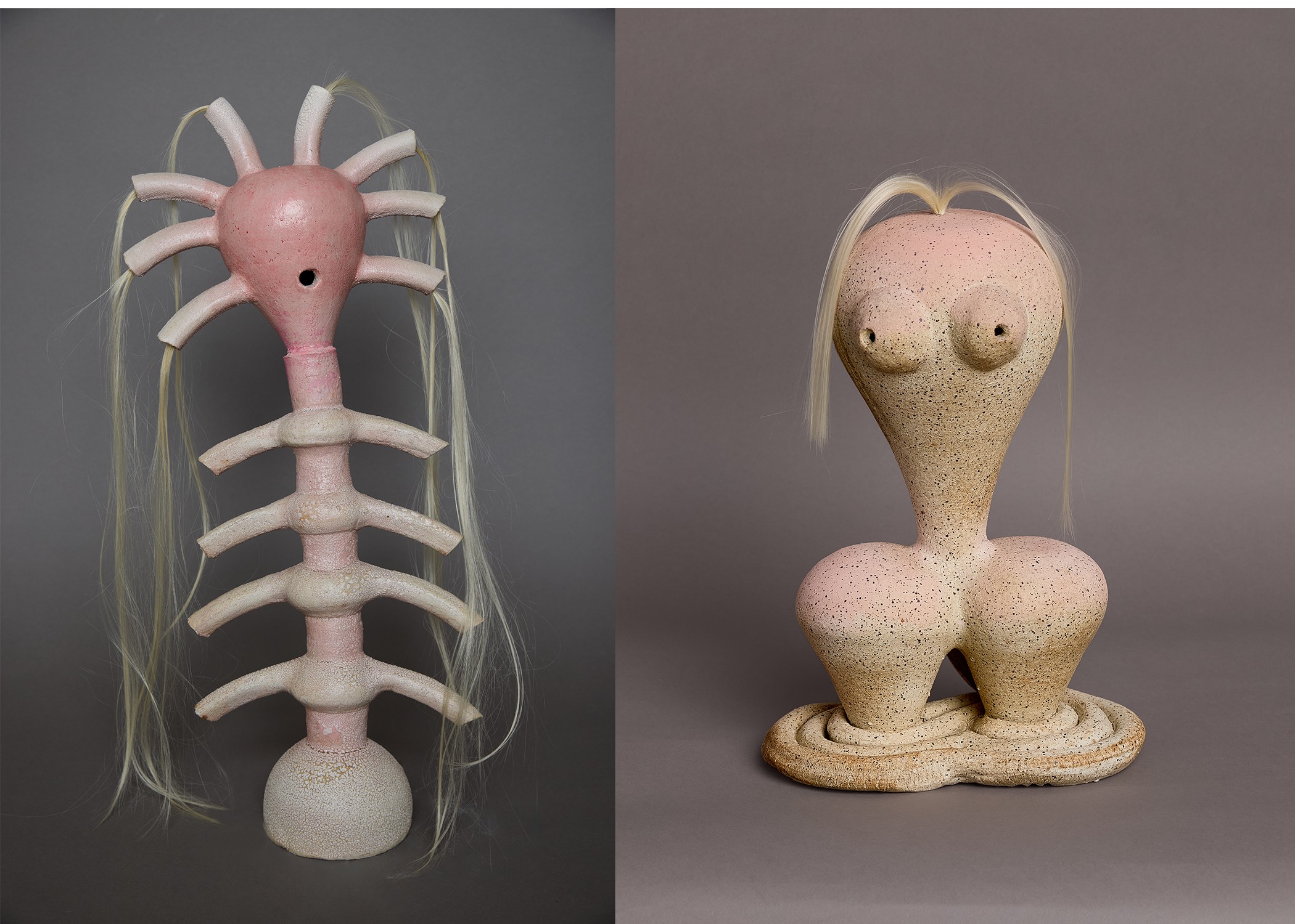 Two sculptures: one resembles a pink and white creature with multiple limbs, the other a beige figure with large breasts and long hair.