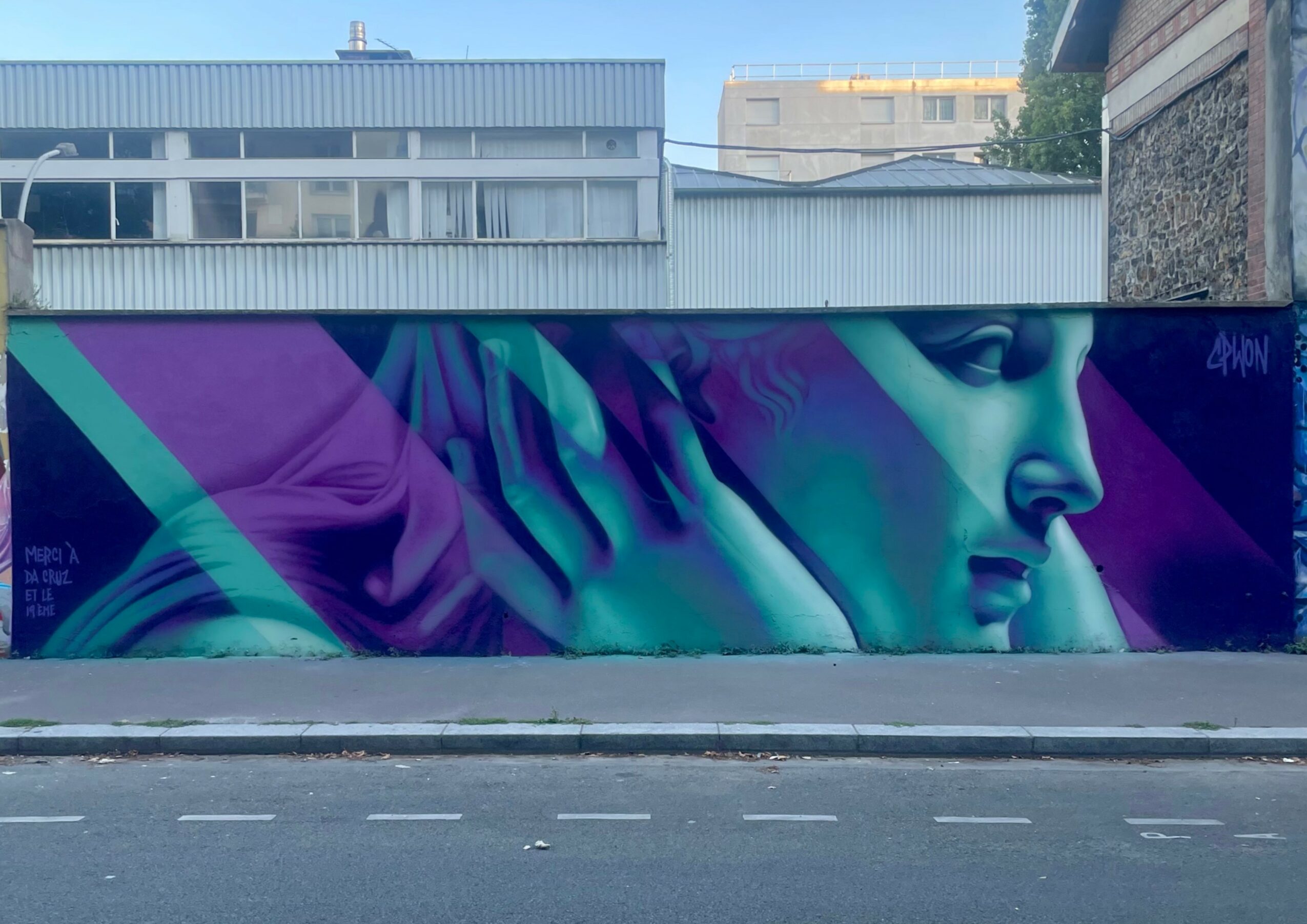 Colorful mural of a woman's face in profile with abstract shapes and vibrant colors, on a city wall.