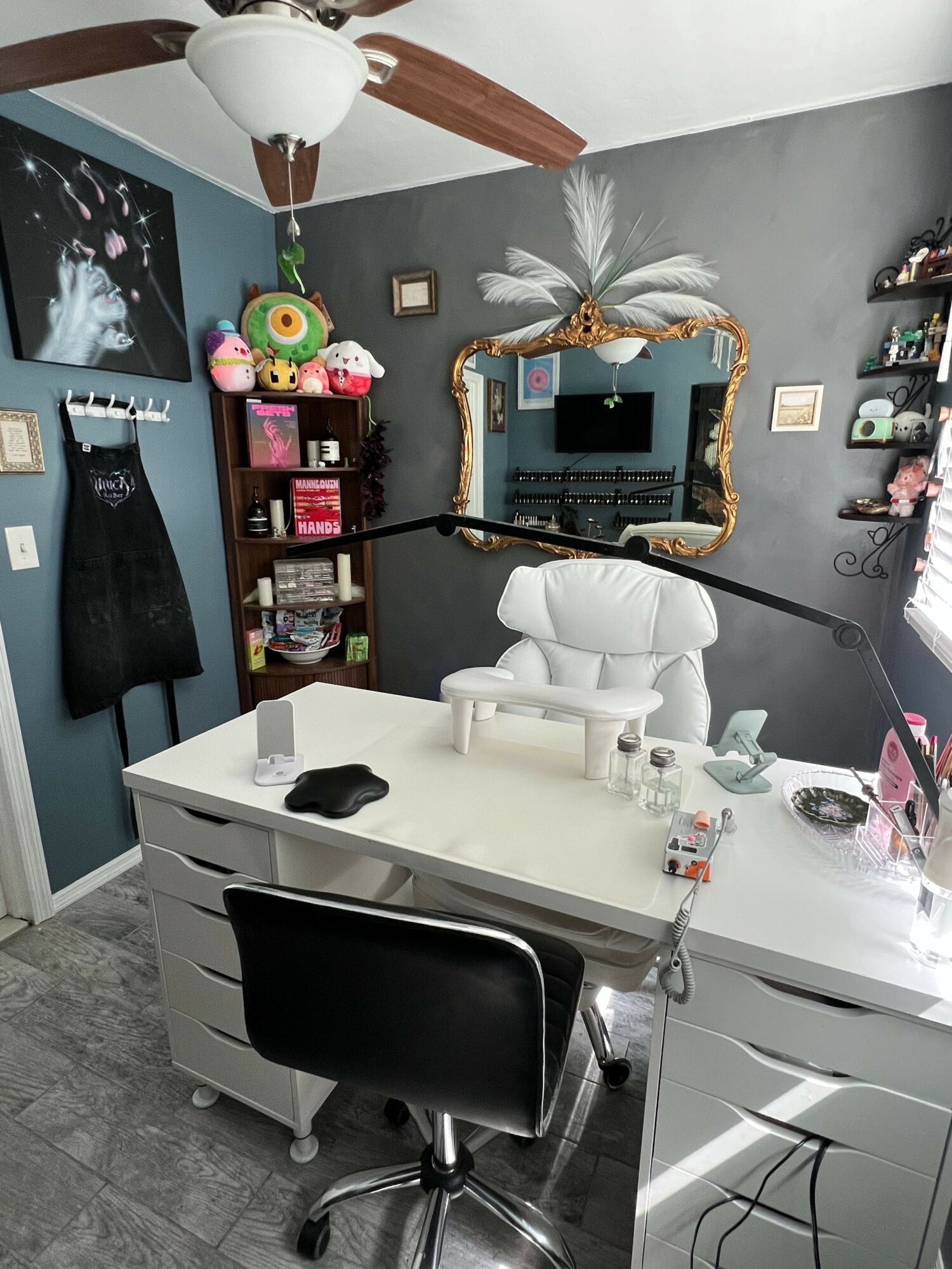 Bathroom vanity with a white sink, black chair, mirror, and decorative items, including plush toys and toiletries.