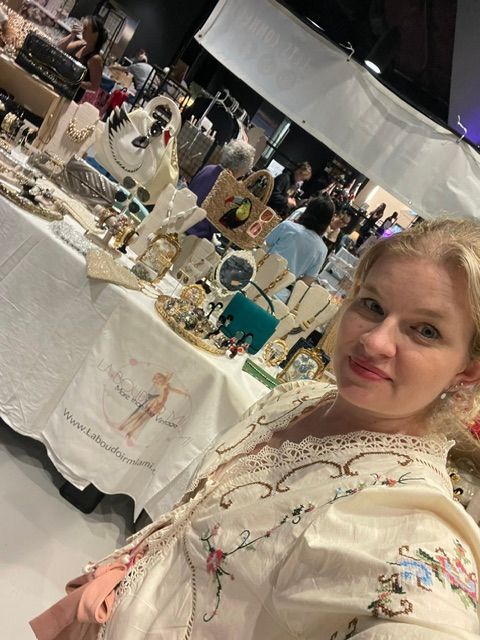 Young girl with blonde hair at a table with various decorative items and a white tablecloth.