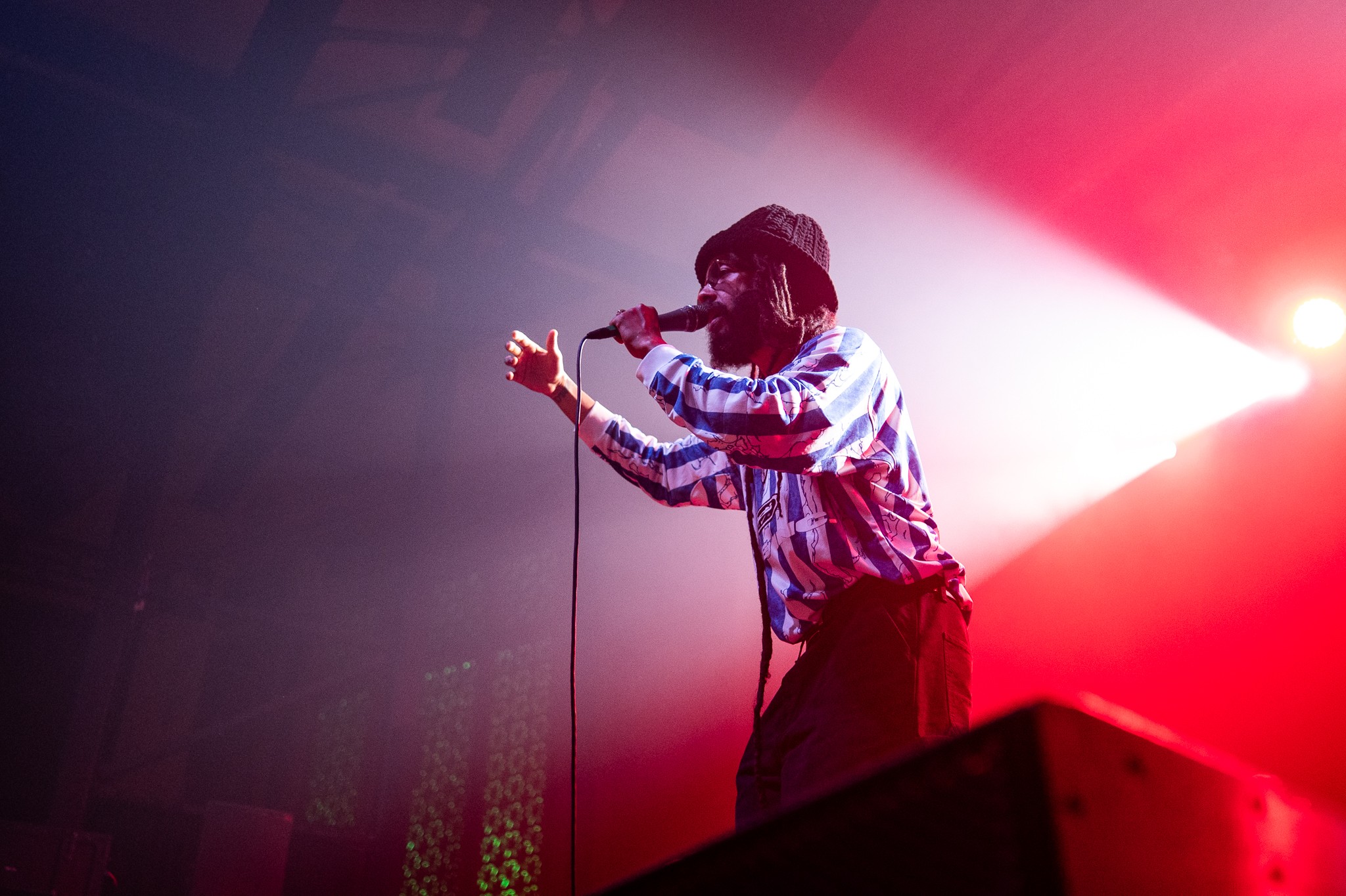Person singing into a microphone on stage with bright red and white lighting effects